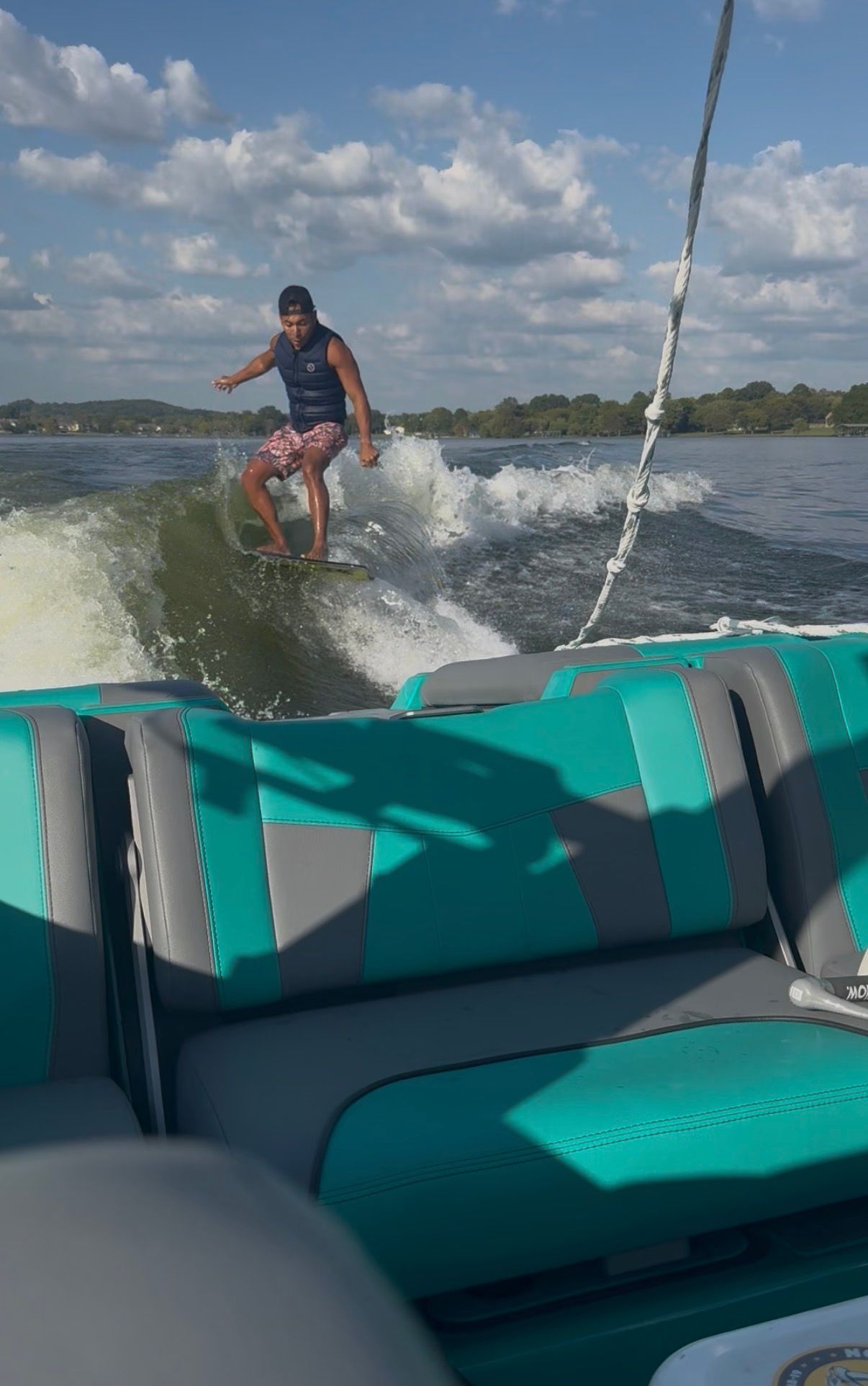 A man surfs behind a Malibu Wakesetter 24 MXZ on a lake.