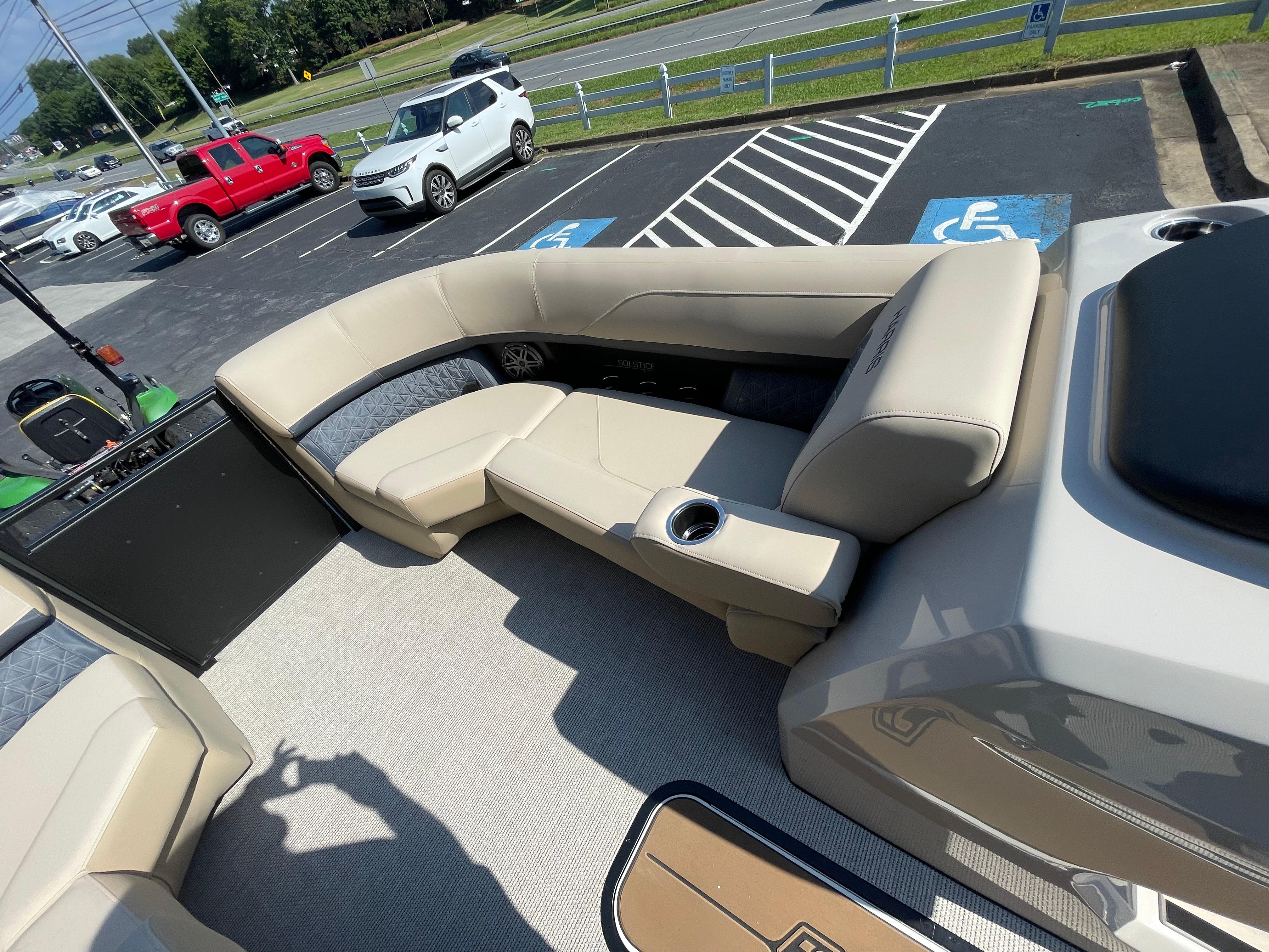 2026 Harris Solstice 230 boat interior with beige seating and cup holders in a parking lot.