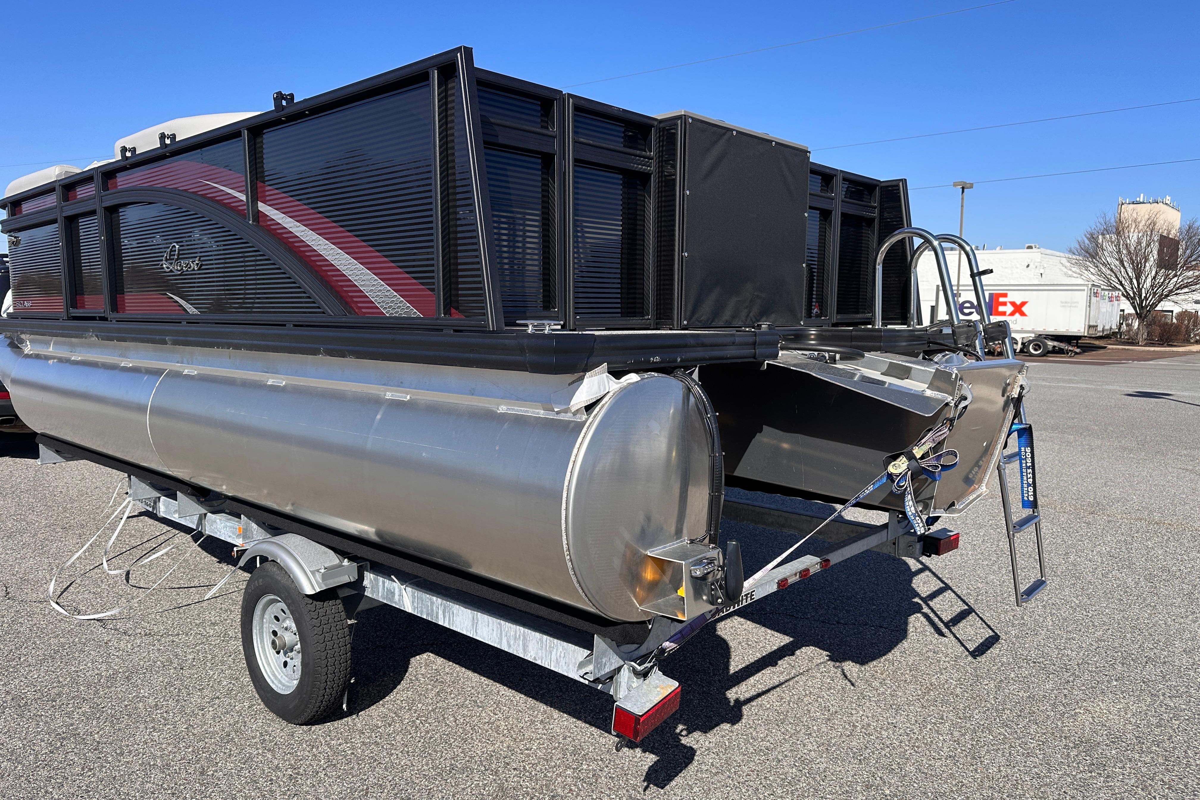2025 Qwest 18 XRE Cruise pontoon boat on trailer, parked outdoors.