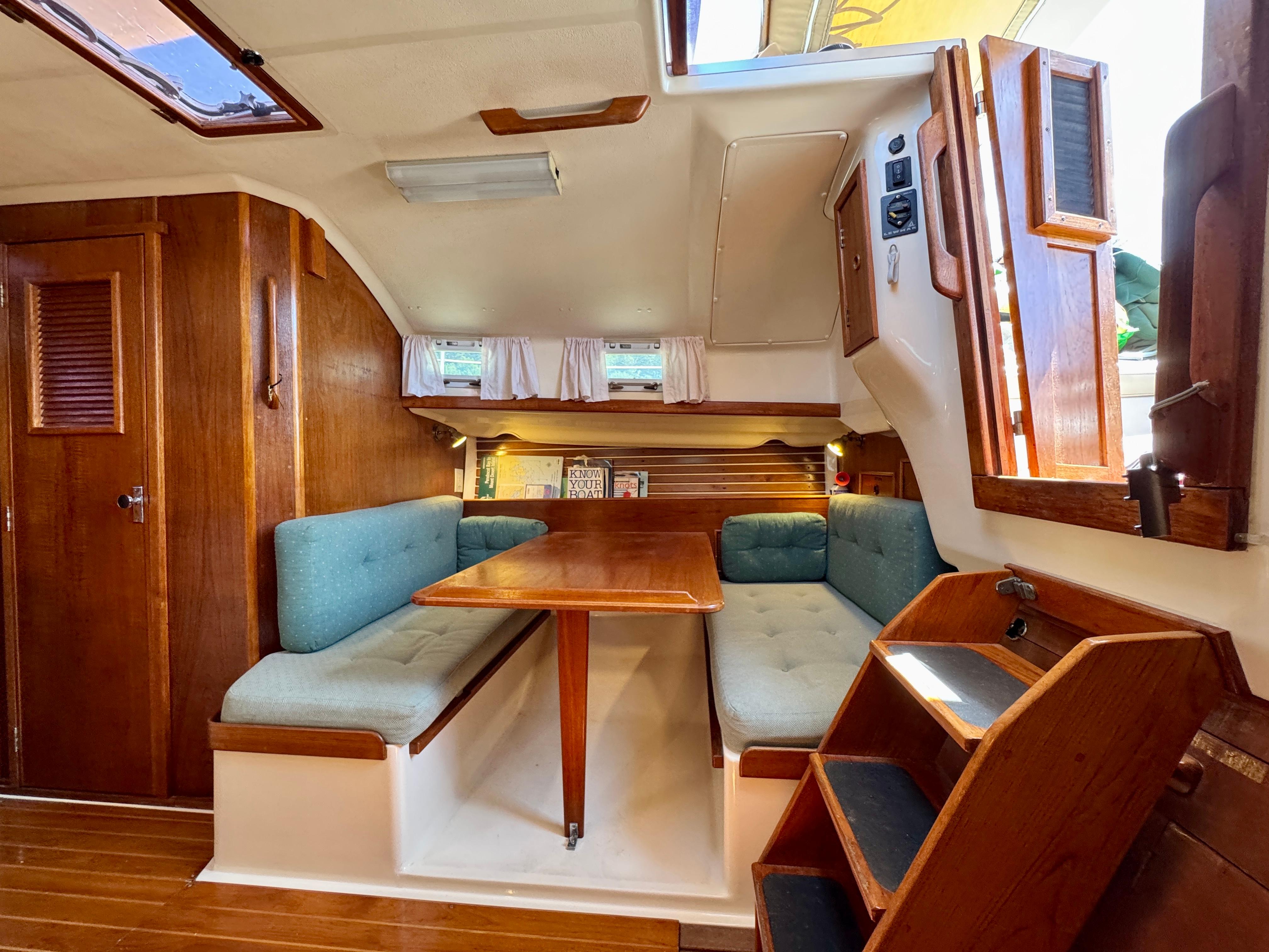 Interior of 1989 Nonsuch 30 Ultra sailboat with wooden furnishings and blue cushioned seating.