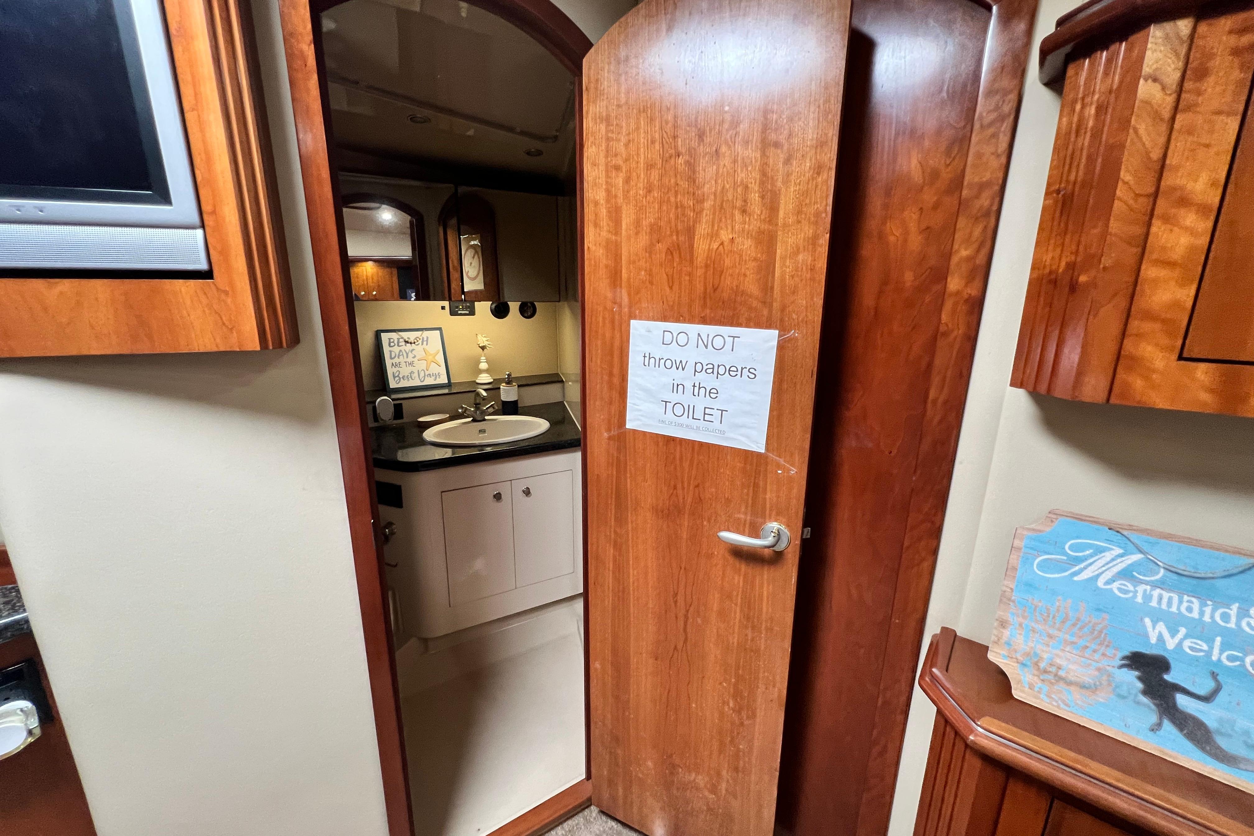 Interior of 2005 Cruisers Yachts 440 Express bathroom with wooden door and sign.