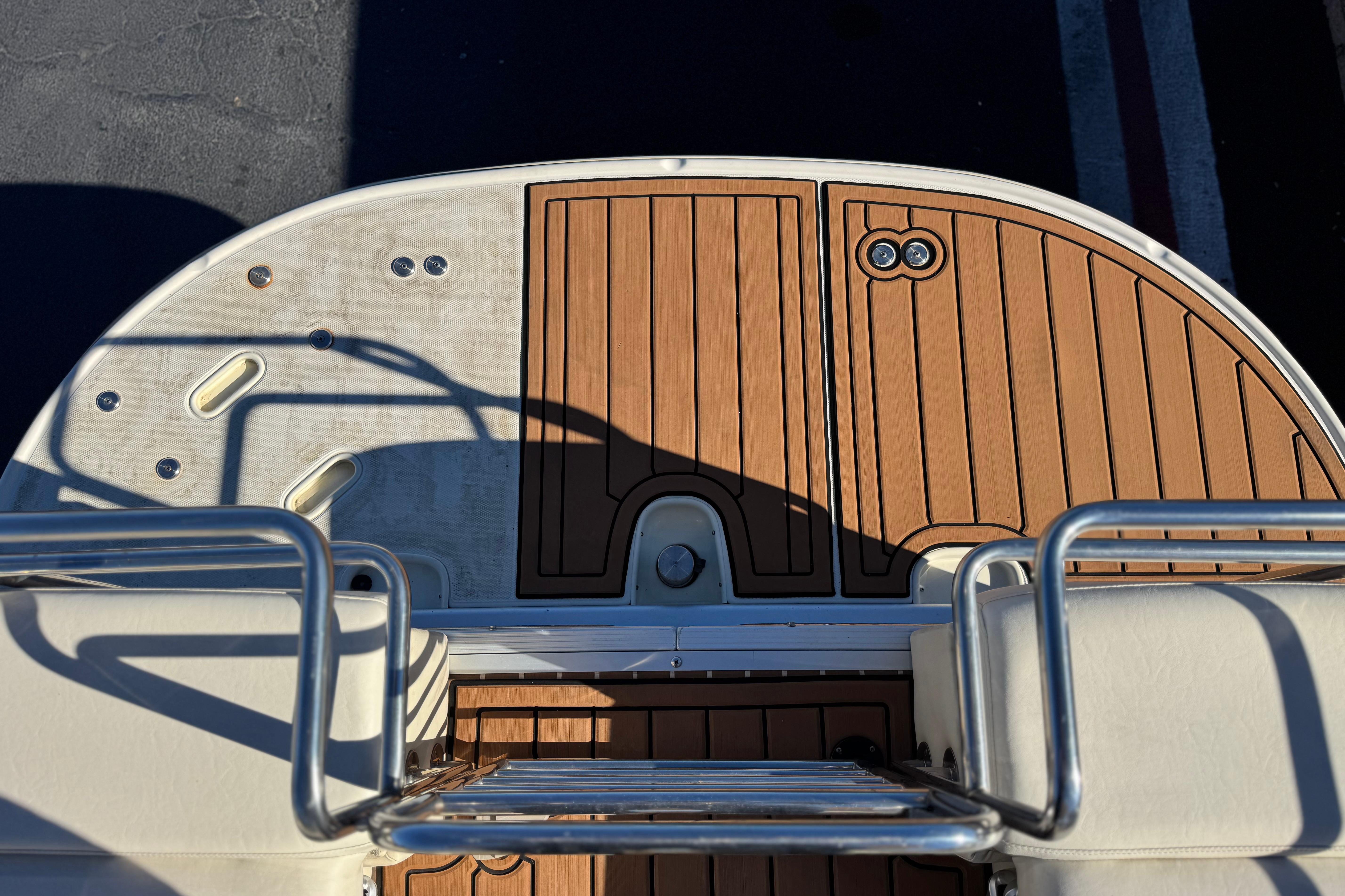 2013 Bennington 2575QCW I/O boat deck with wood finish and metal railings.