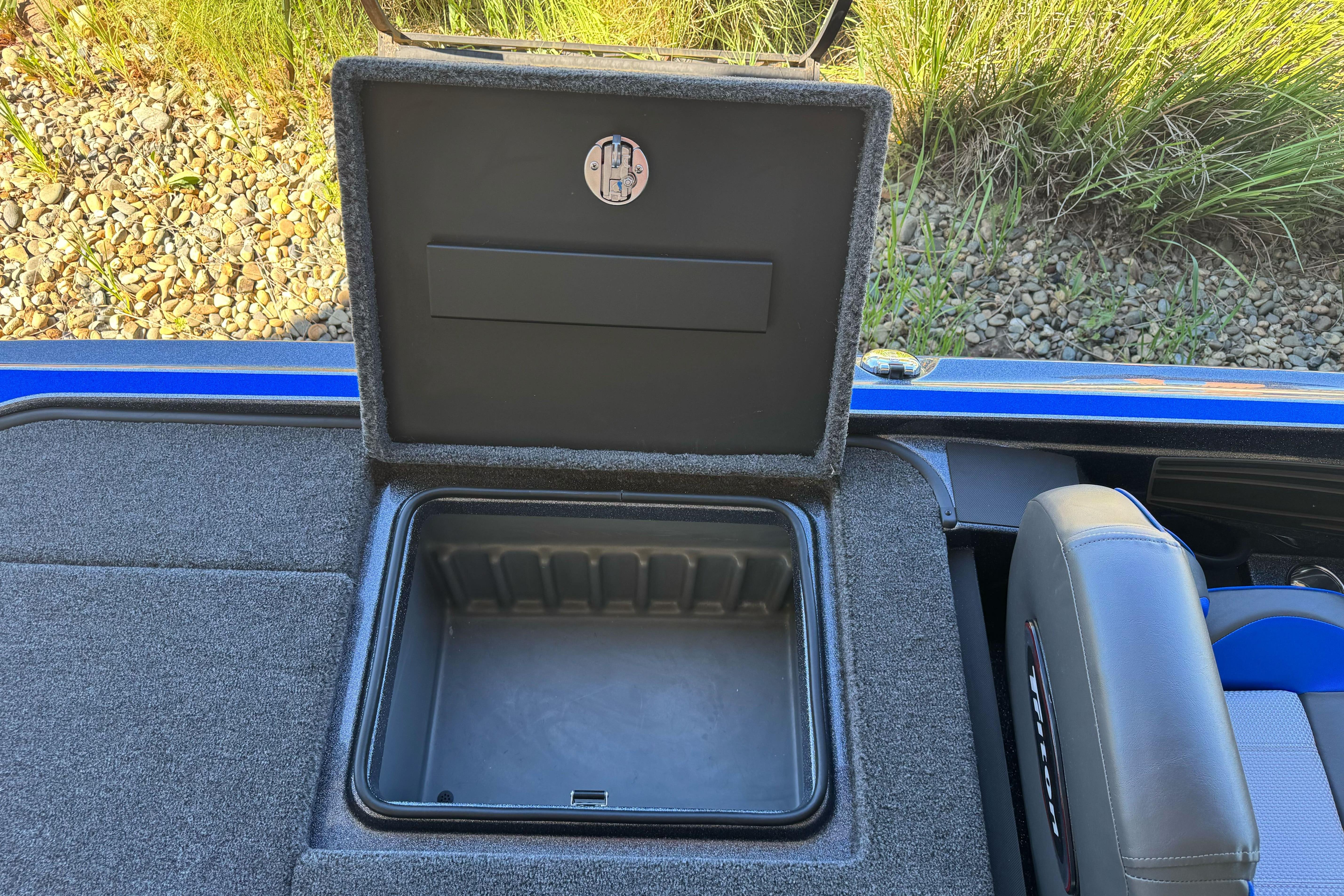 Open storage compartment in 2026 Triton 21XP Patriot boat, featuring carpeted interior and sleek design.