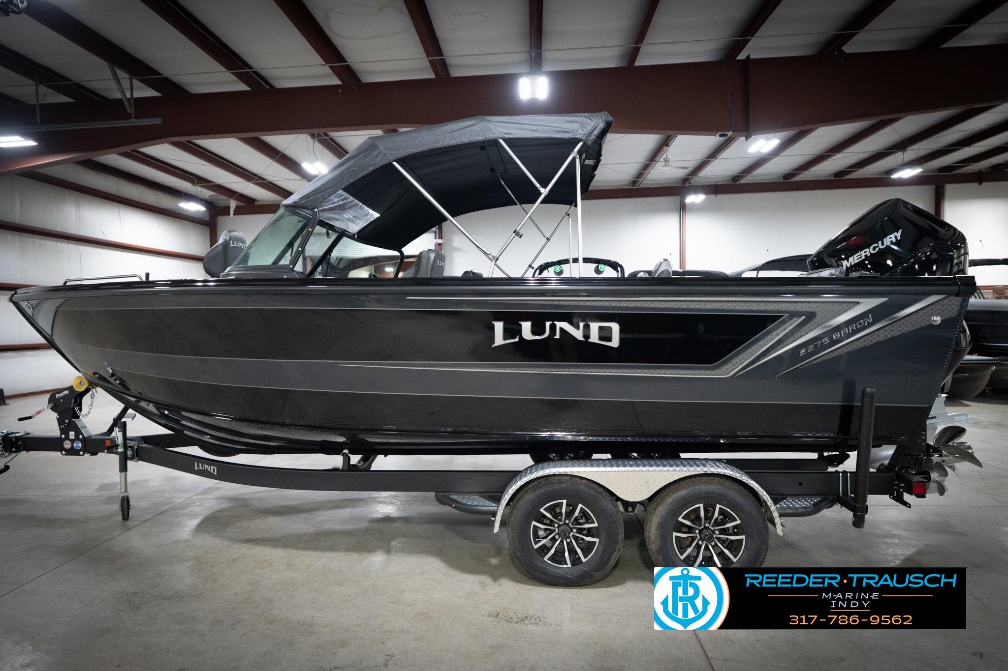 2026 Lund 2275 Baron boat in showroom, featuring sleek black design and Mercury engine.