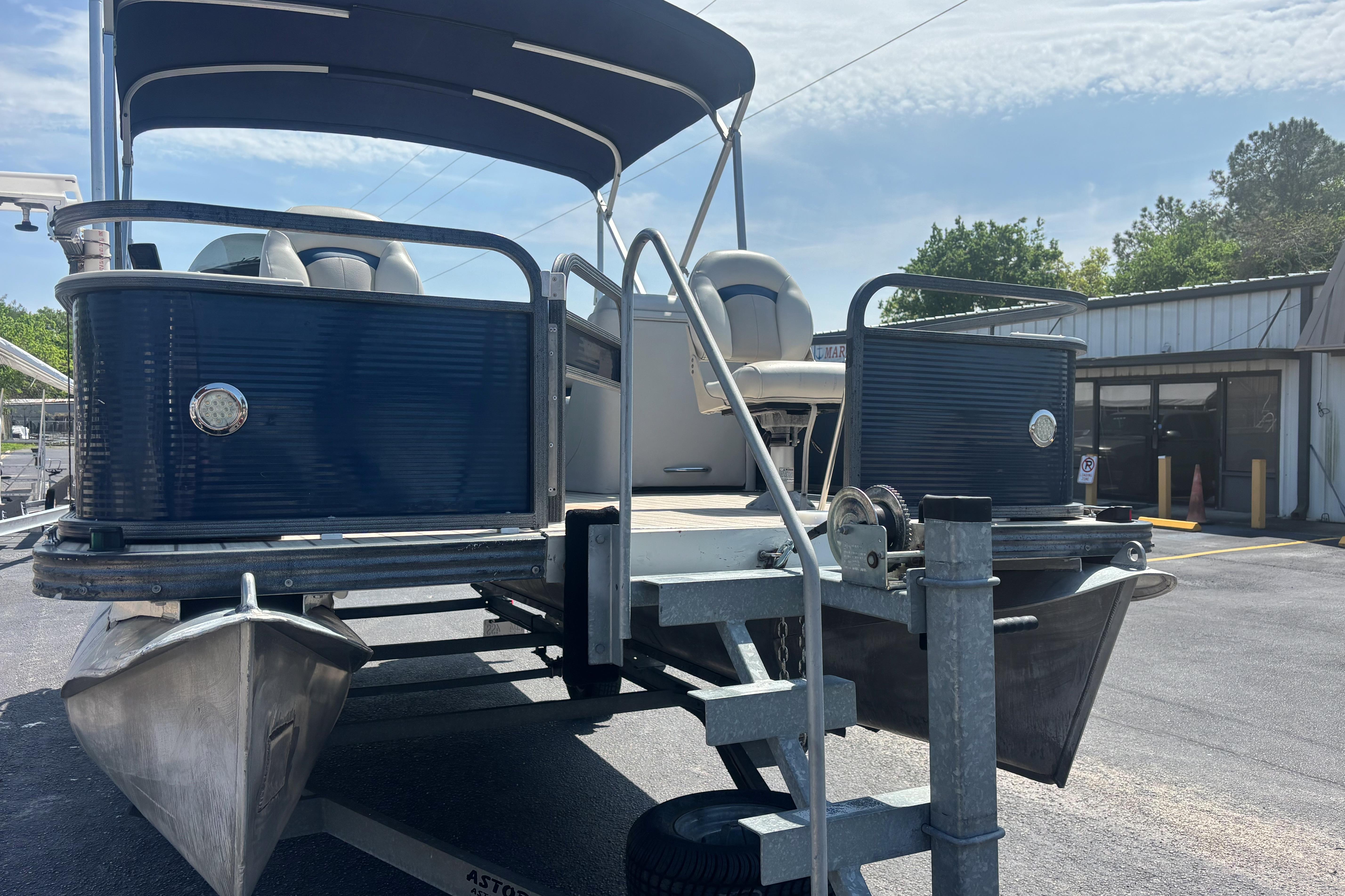 2015 Manitou 20 Oasis Angler pontoon boat on trailer, blue exterior, sunny day.