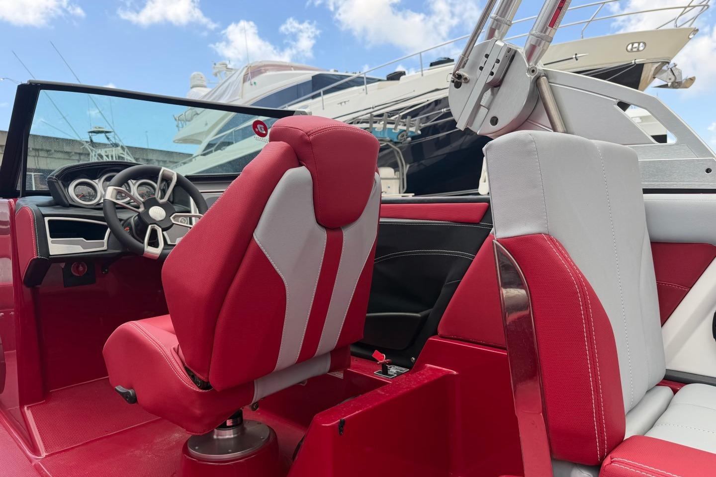 2023 MasterCraft X24 boat interior with red and white seating, steering wheel, and dashboard.
