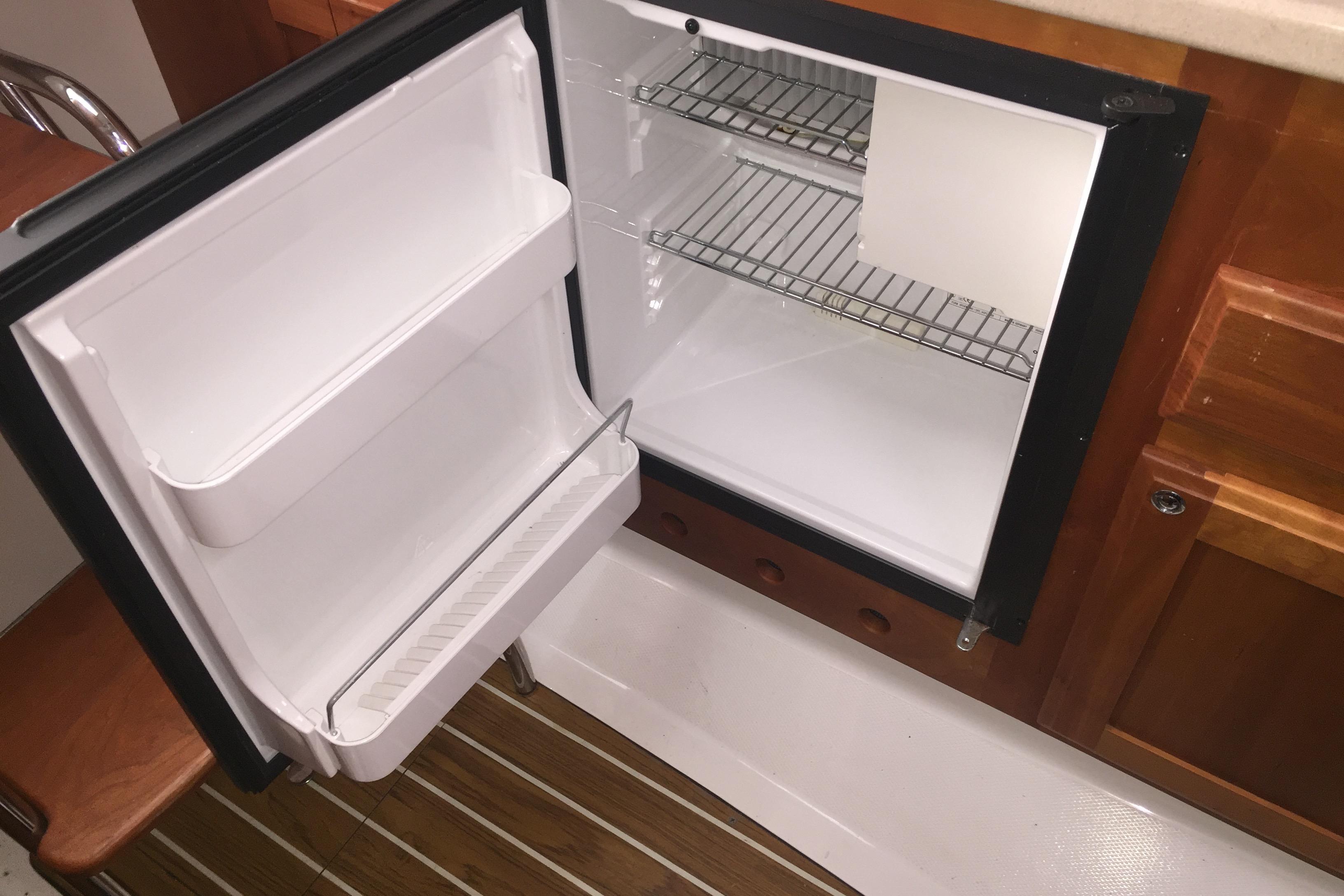 Open refrigerator inside 2007 Back Cove 29 boat, featuring wooden cabinetry and shelving.