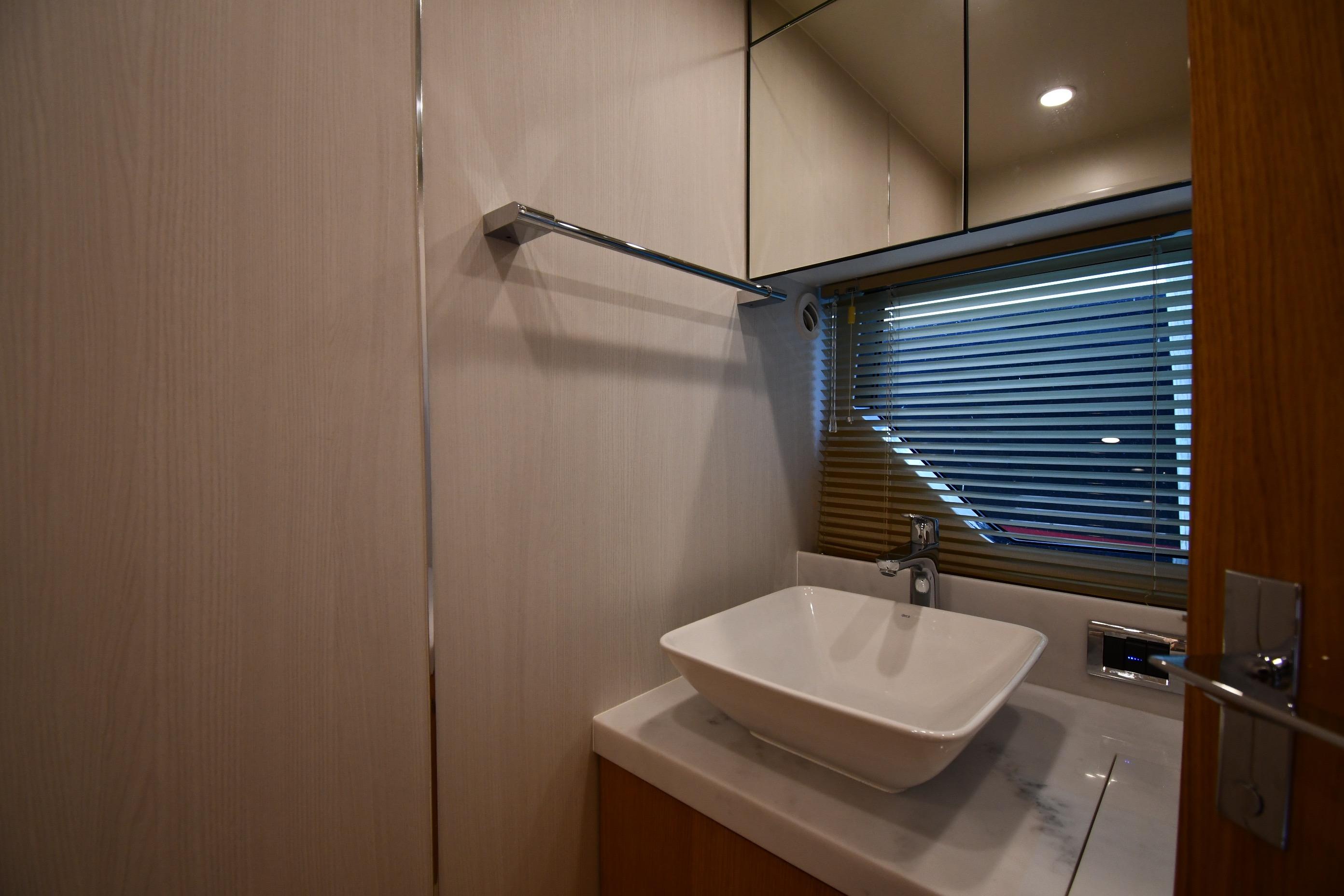 Modern bathroom interior of 2024 Fairline G50 Targa yacht with sleek sink and blinds.