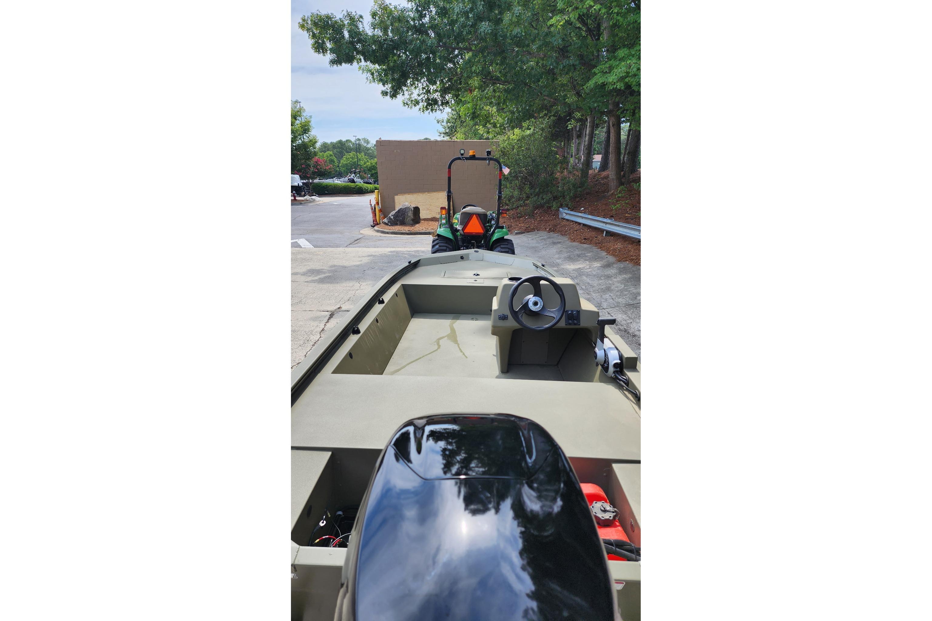 2026 Tracker Grizzly 1648 SC boat with steering console, parked outdoors near trees.