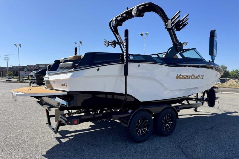 2026 MasterCraft XT22 boat on trailer in parking lot, side view.
