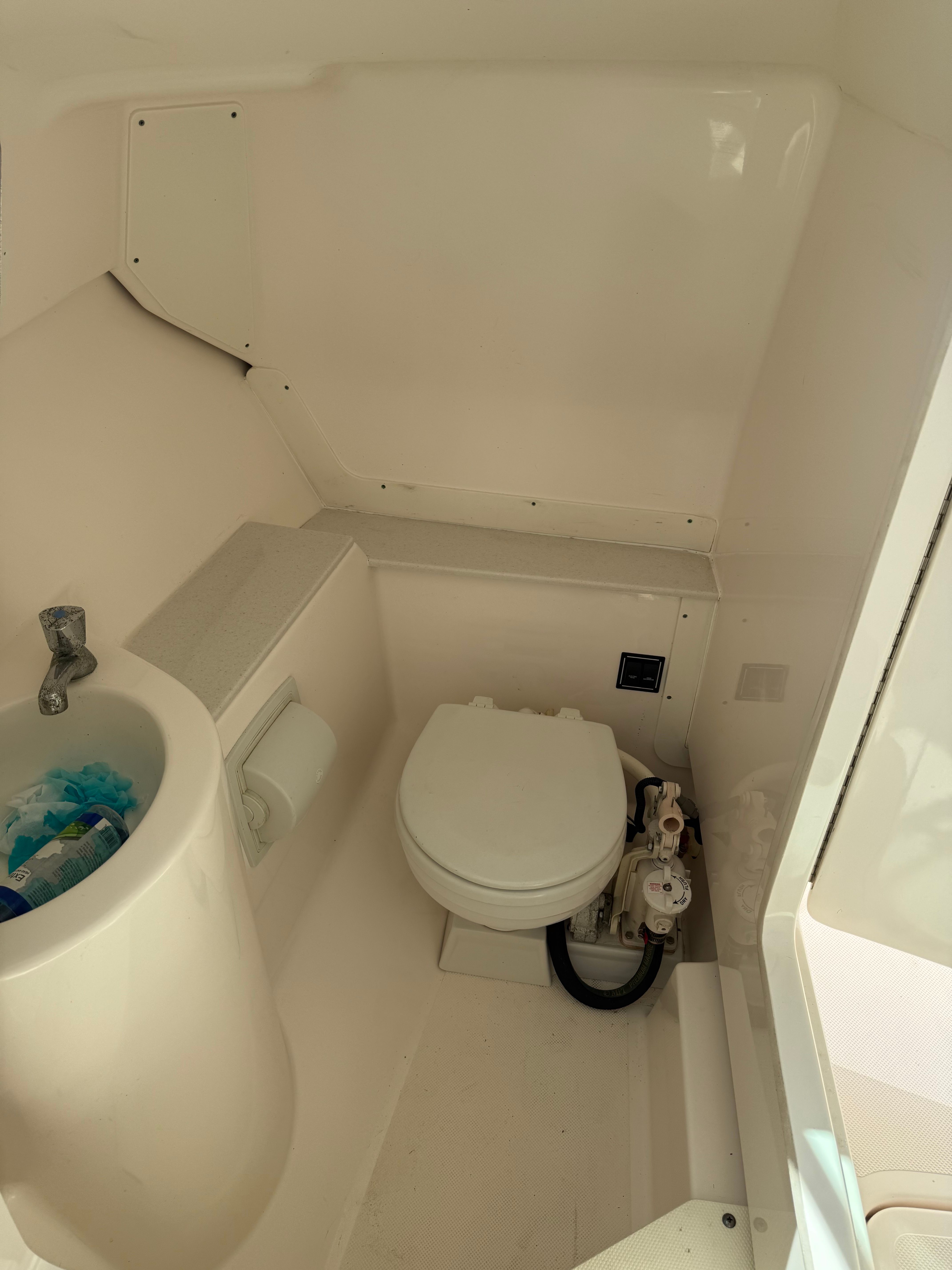 The image shows a compact boat bathroom with a sink and toilet.