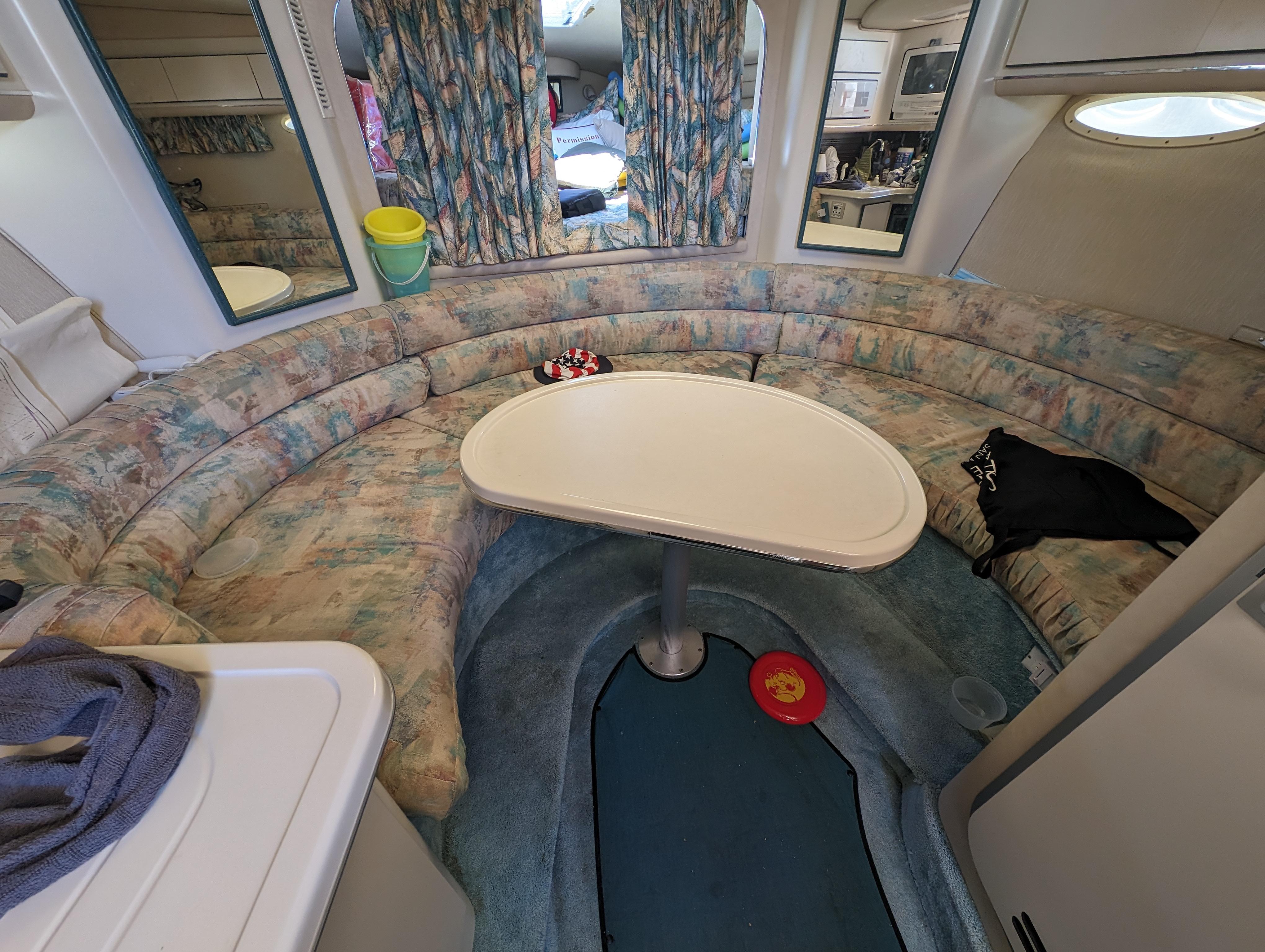 Interior of a 1995 Sea Ray 380 Sun Sport boat with a curved seating area and table.