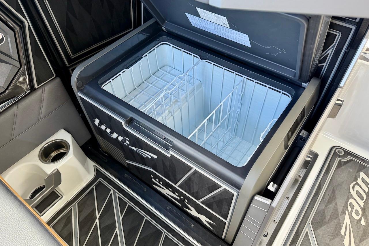 Open cooler compartment in 2025 Tigé Ultré 25ZX boat, featuring sleek design and cup holder.