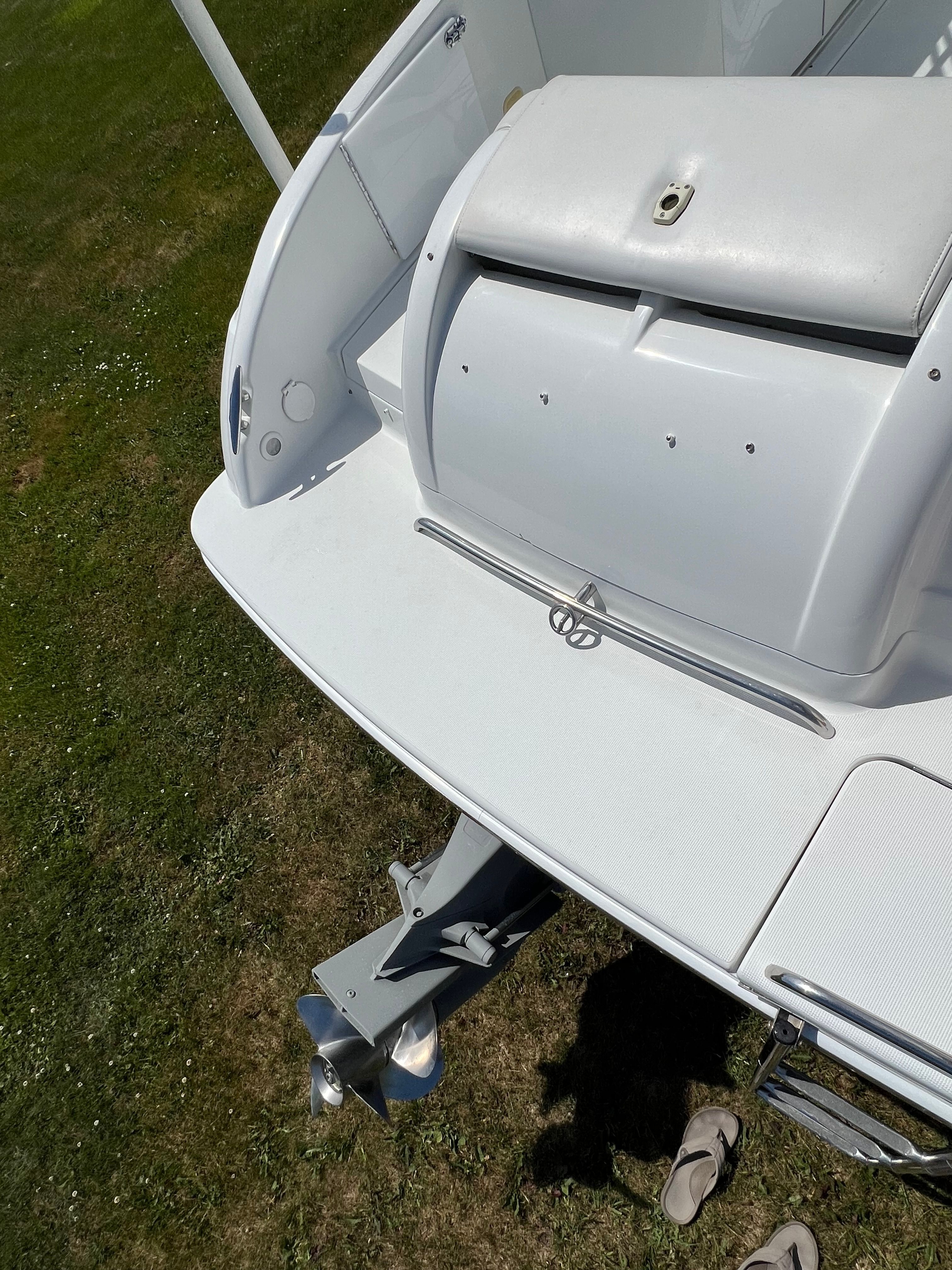 The image shows the stern of a white boat with a swim platform and an engine.