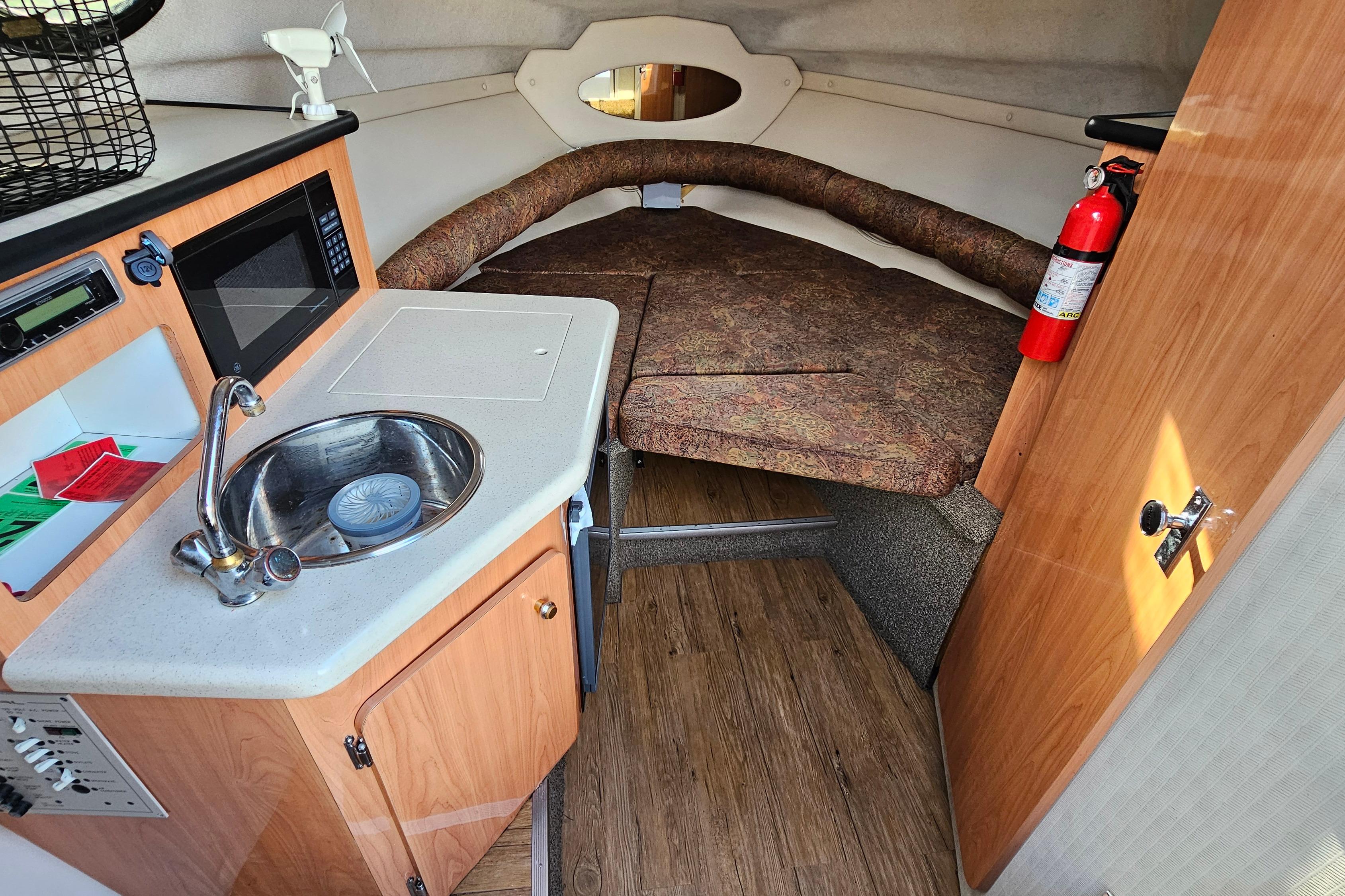 1999 Regal Commodore 258 cabin interior with kitchenette, sink, and cozy sleeping area.