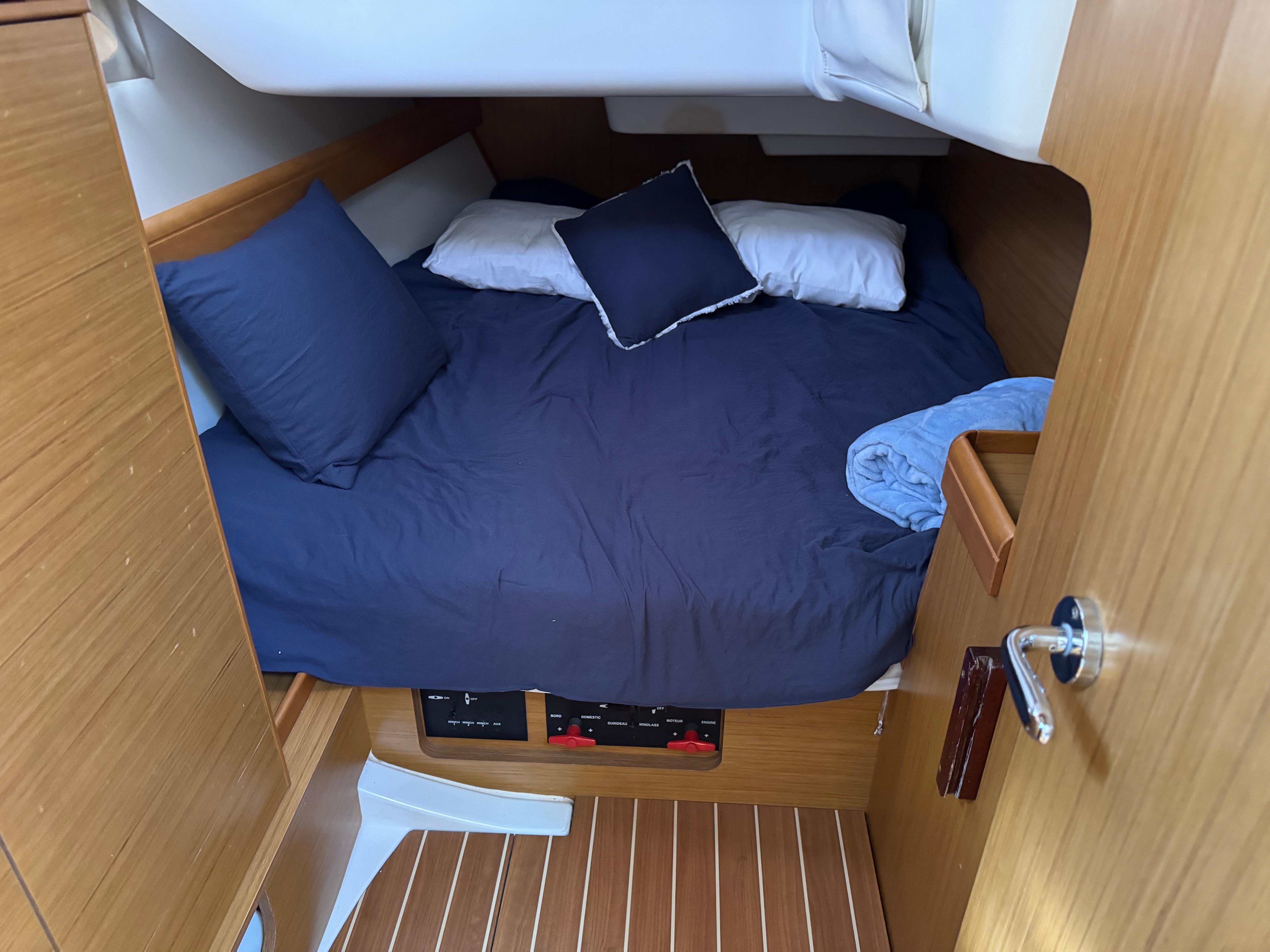 Cozy cabin interior of 2008 Jeanneau Sun Odyssey 42 I sailboat with blue bedding.