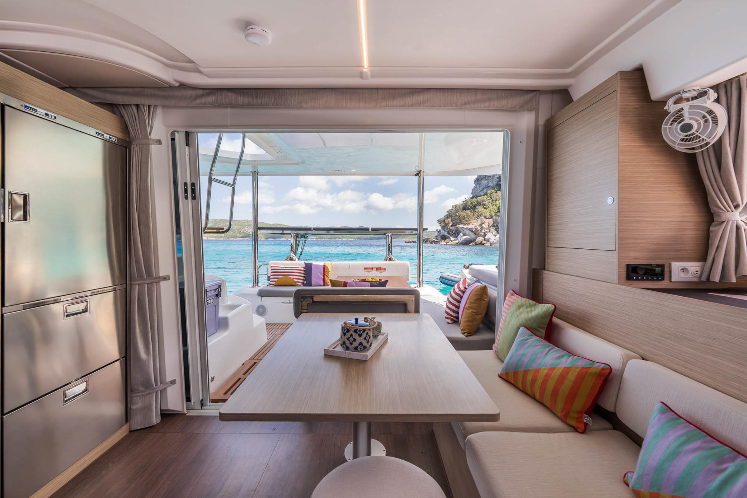 Interior of 2025 Lagoon 38 catamaran with ocean view, colorful cushions, and modern design.