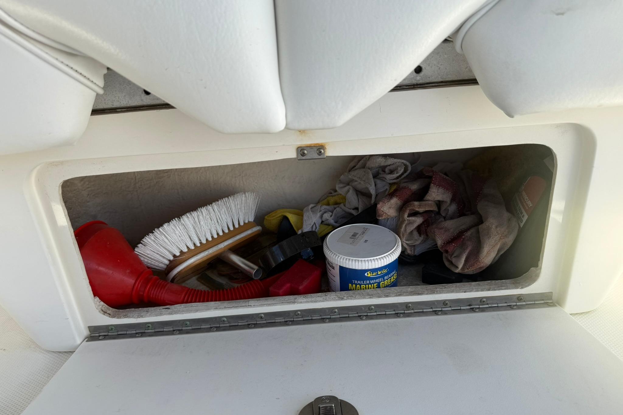 Storage compartment on a 2006 Sea Ray 270 Amberjack with cleaning supplies and tools.