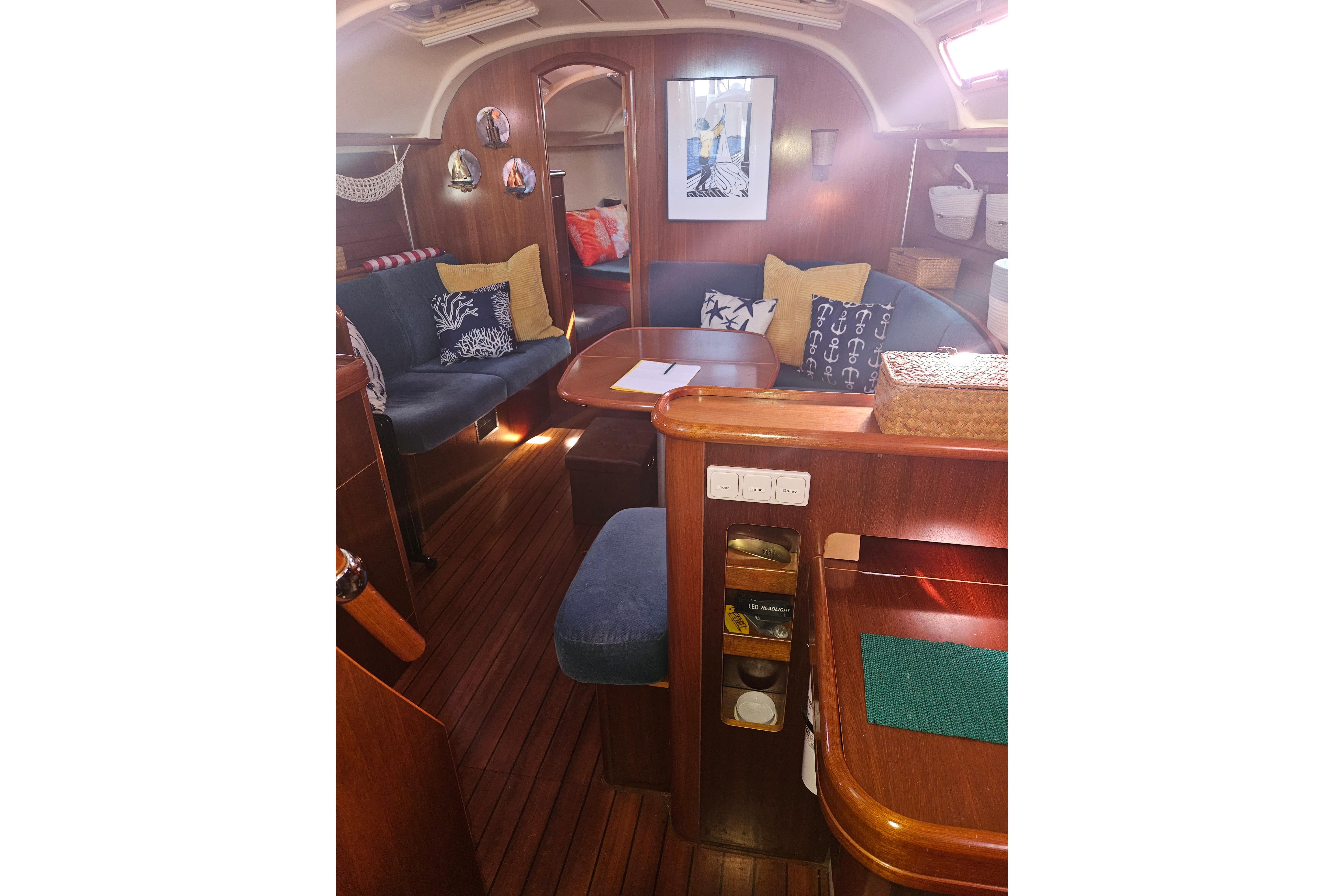 Interior of 1998 Beneteau 381 sailboat with cozy seating and nautical decor.