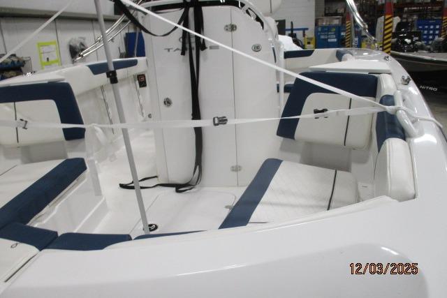 2024 Tahoe 2150 CC boat interior with blue and white seating in a showroom.