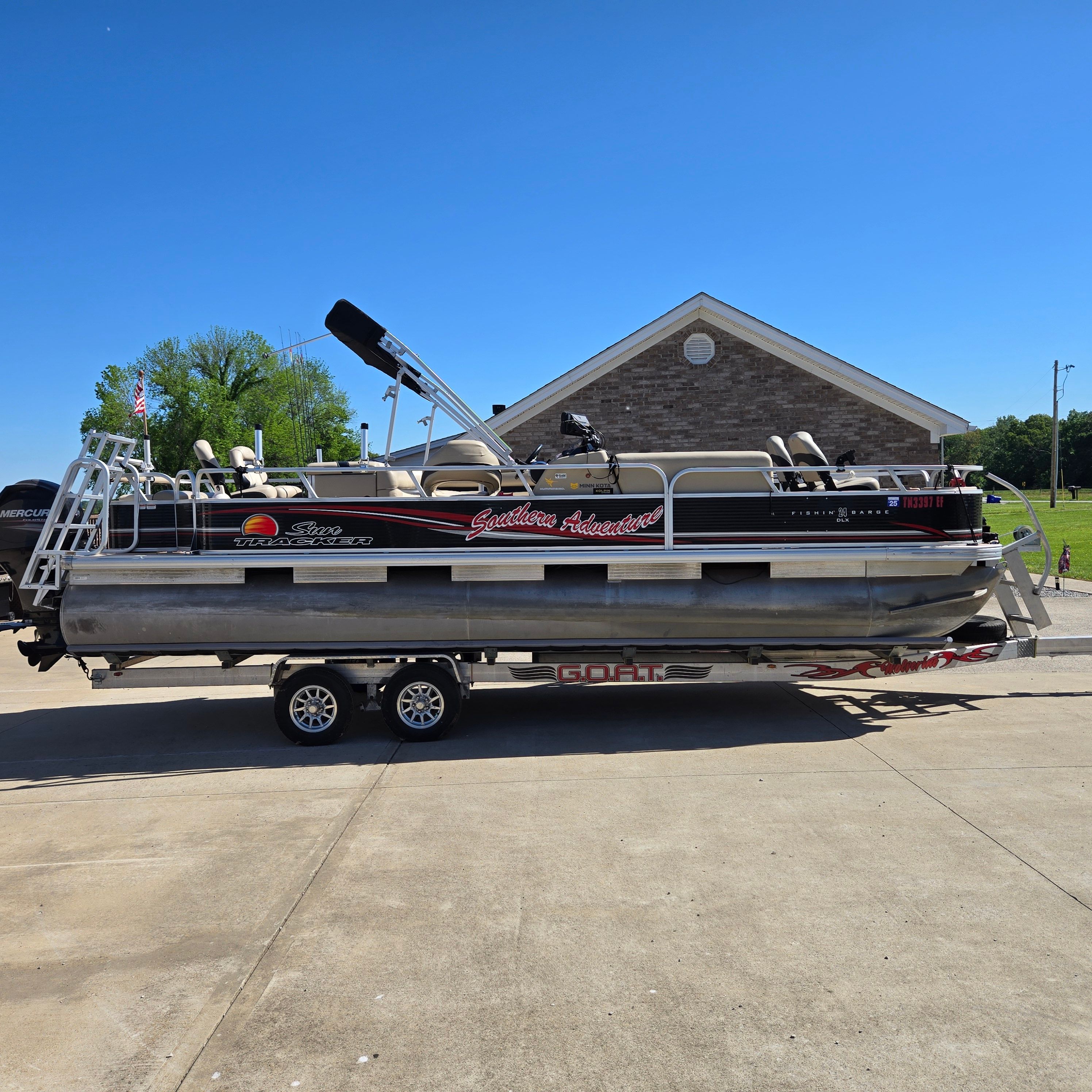 A 2012 Sun Tracker Fishin' Barge 24 DLX on a trailer in a parking lot.