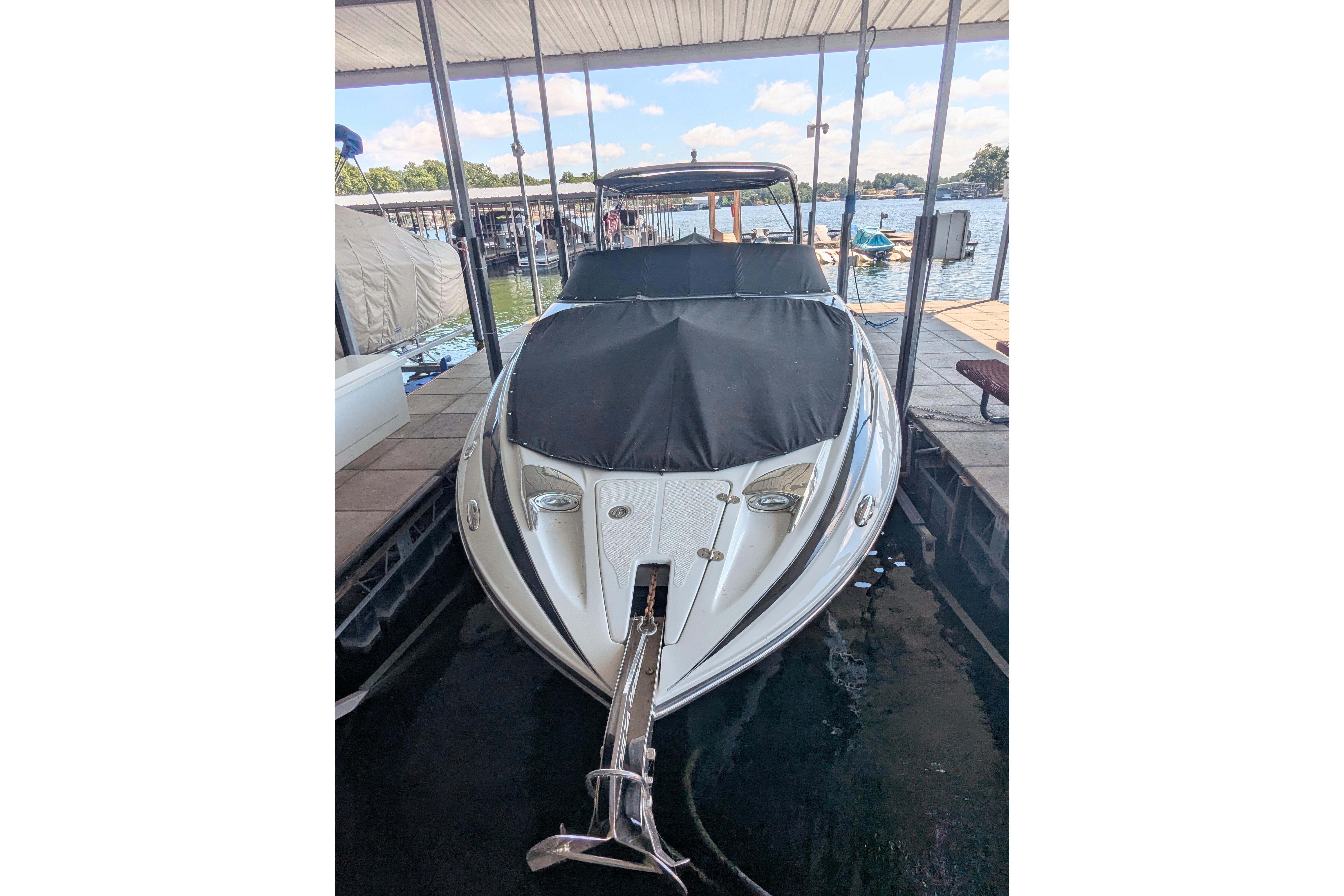 2008 Crownline 300 LS boat docked, covered, and ready for use on a sunny day.