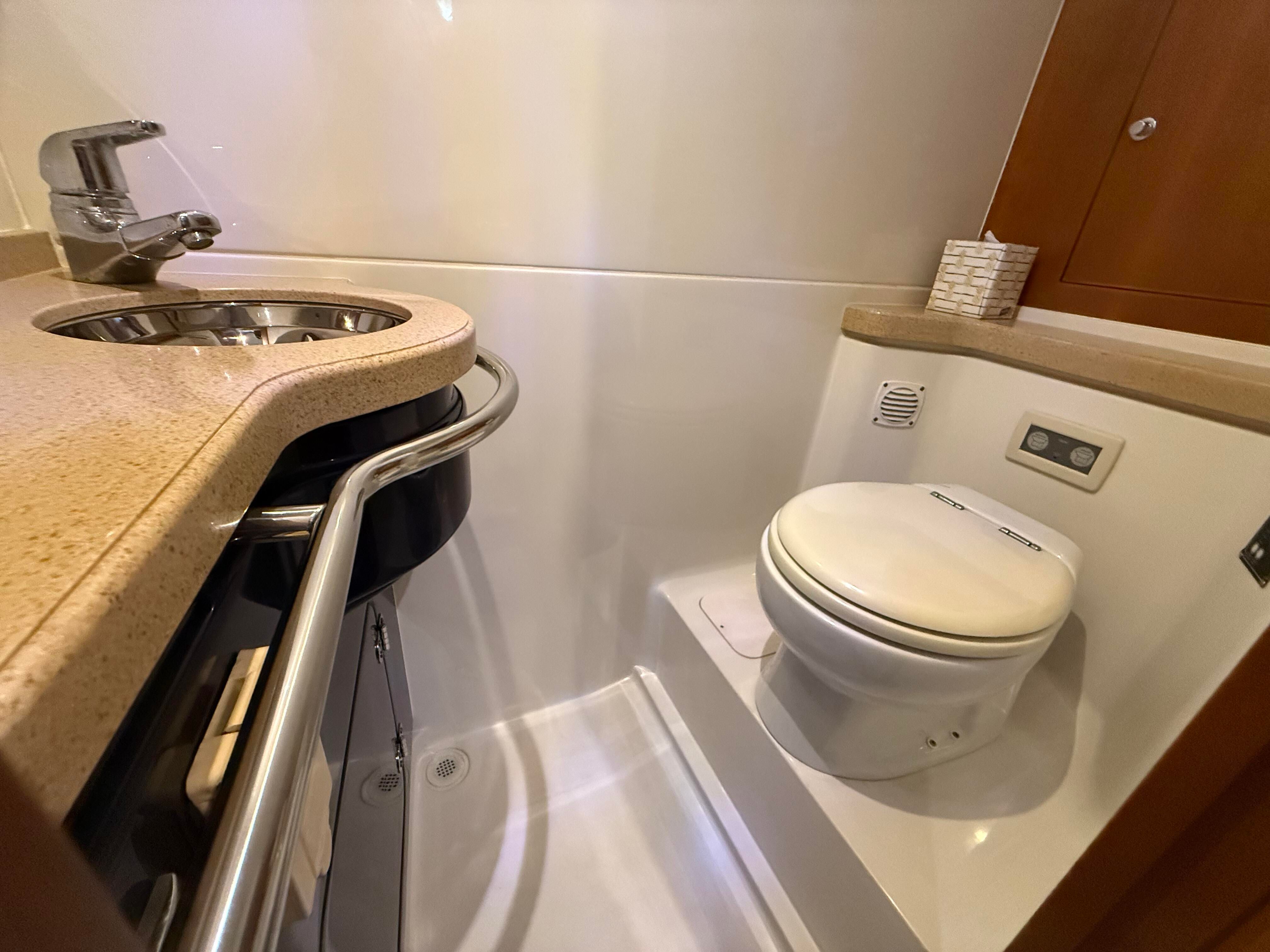 Interior view of a boat cabin with a sink and toilet, featuring sleek design.