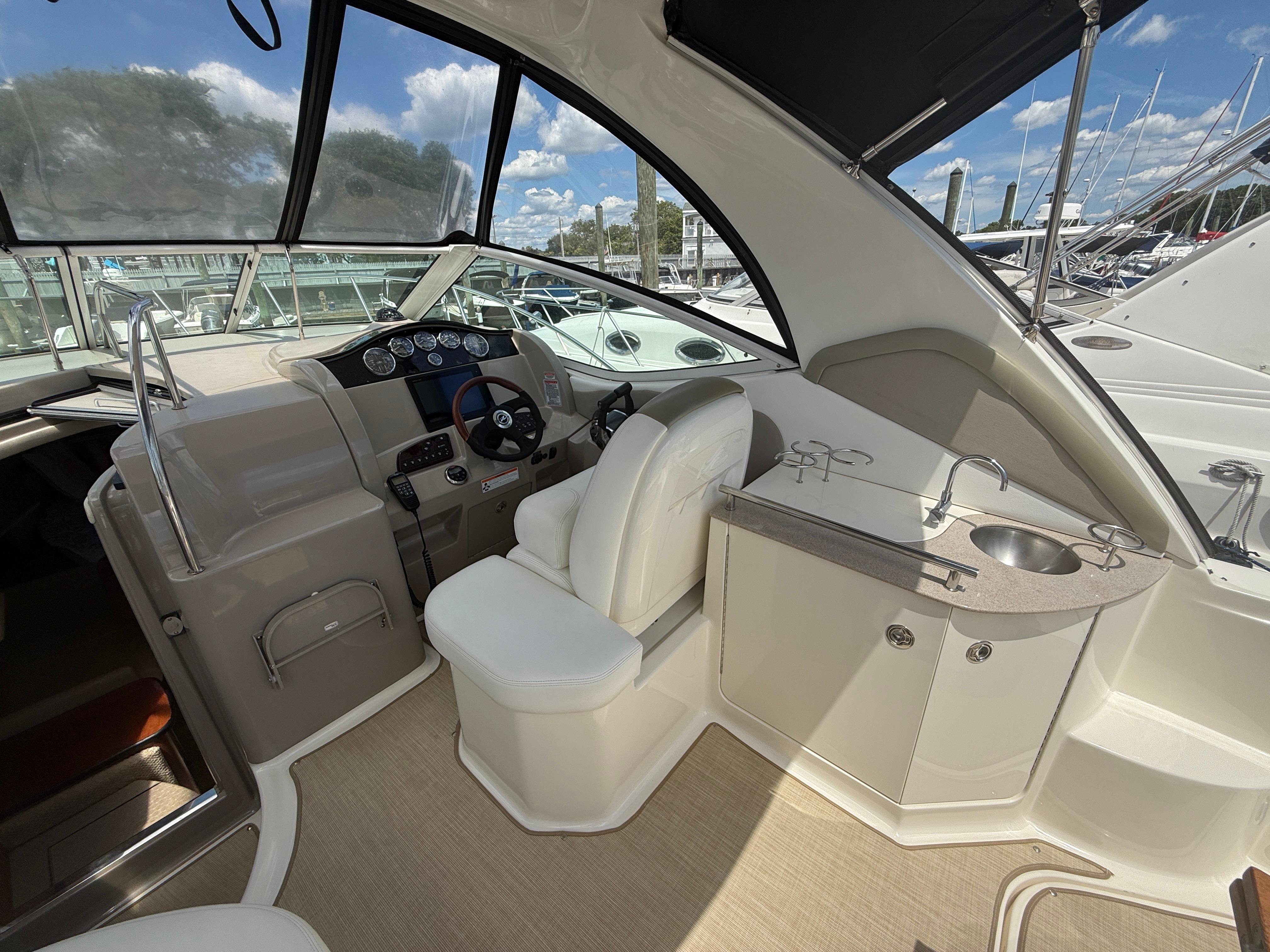 2006 Sea Ray 290 Sundancer cockpit with helm, seating, and sink under a clear sky.