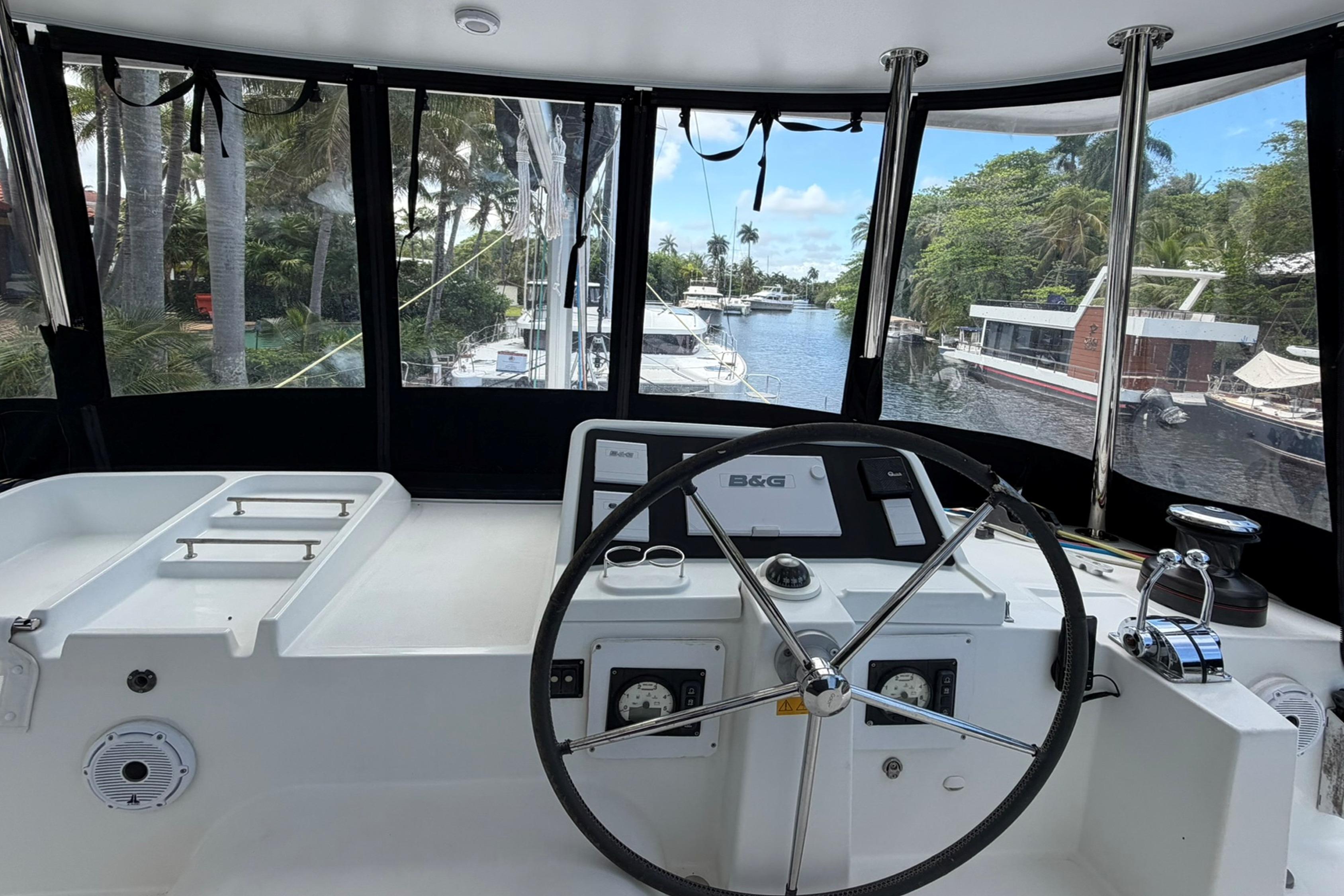 Helm of 2018 Lagoon 450 catamaran with marina view through windows.