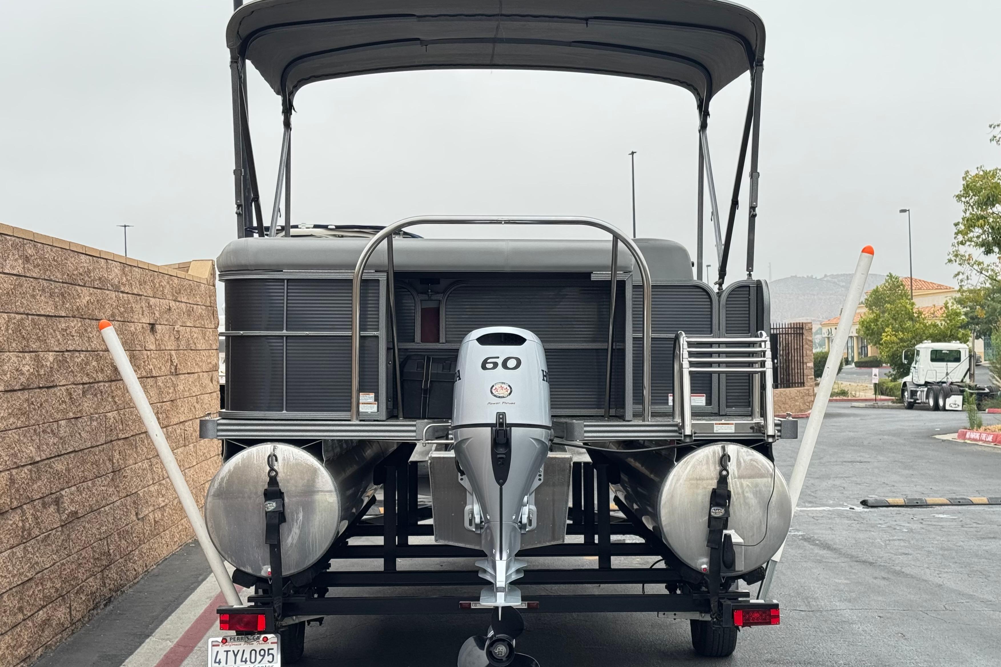 2020 Manitou 18 Aurora LE pontoon boat with Honda outboard motor, parked on a trailer.