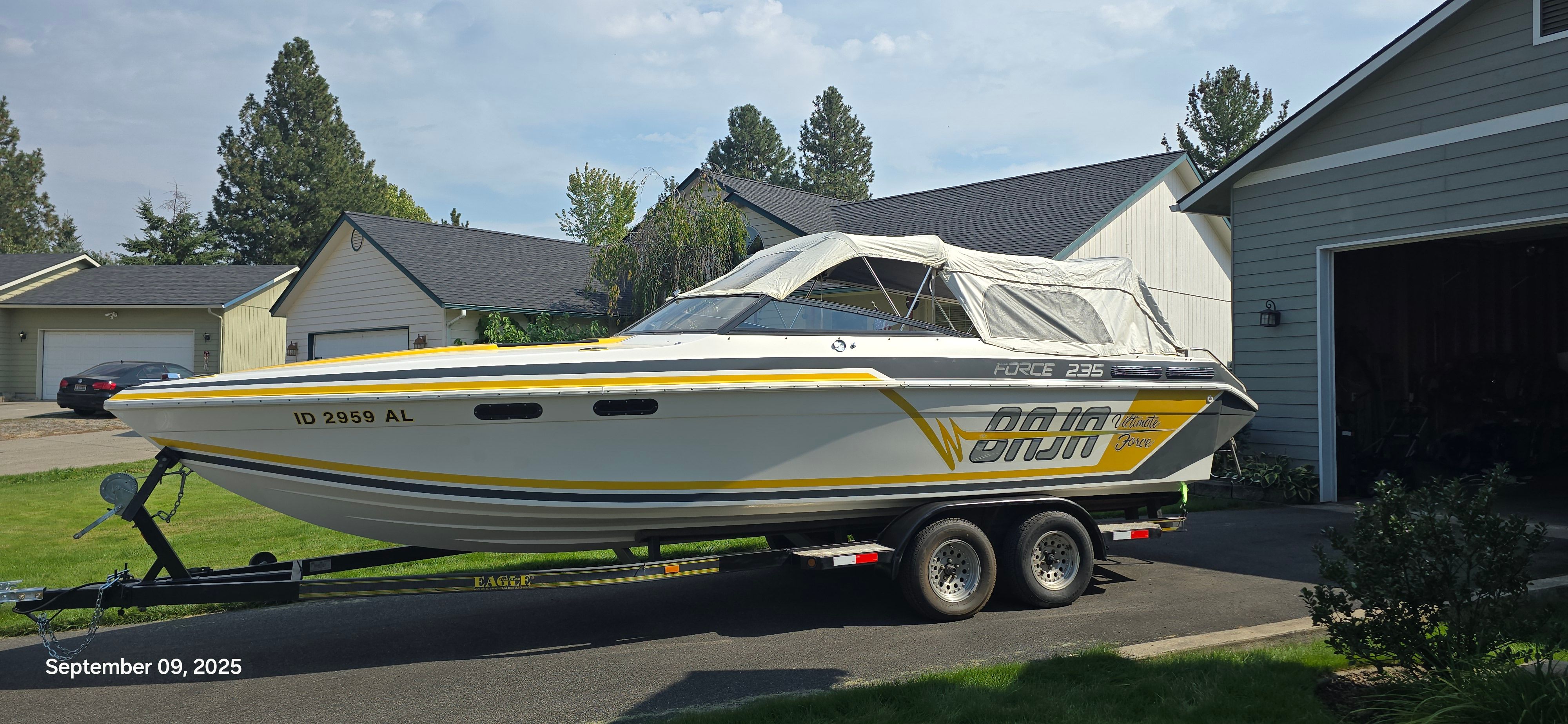 A 1989 Baja FORCE 235 boat on a trailer in a residential area.