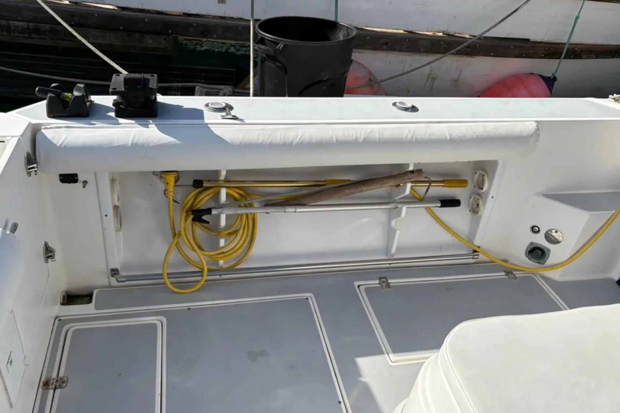 2005 Albin 28 Tournament Express boat deck with storage compartment and coiled yellow hose.
