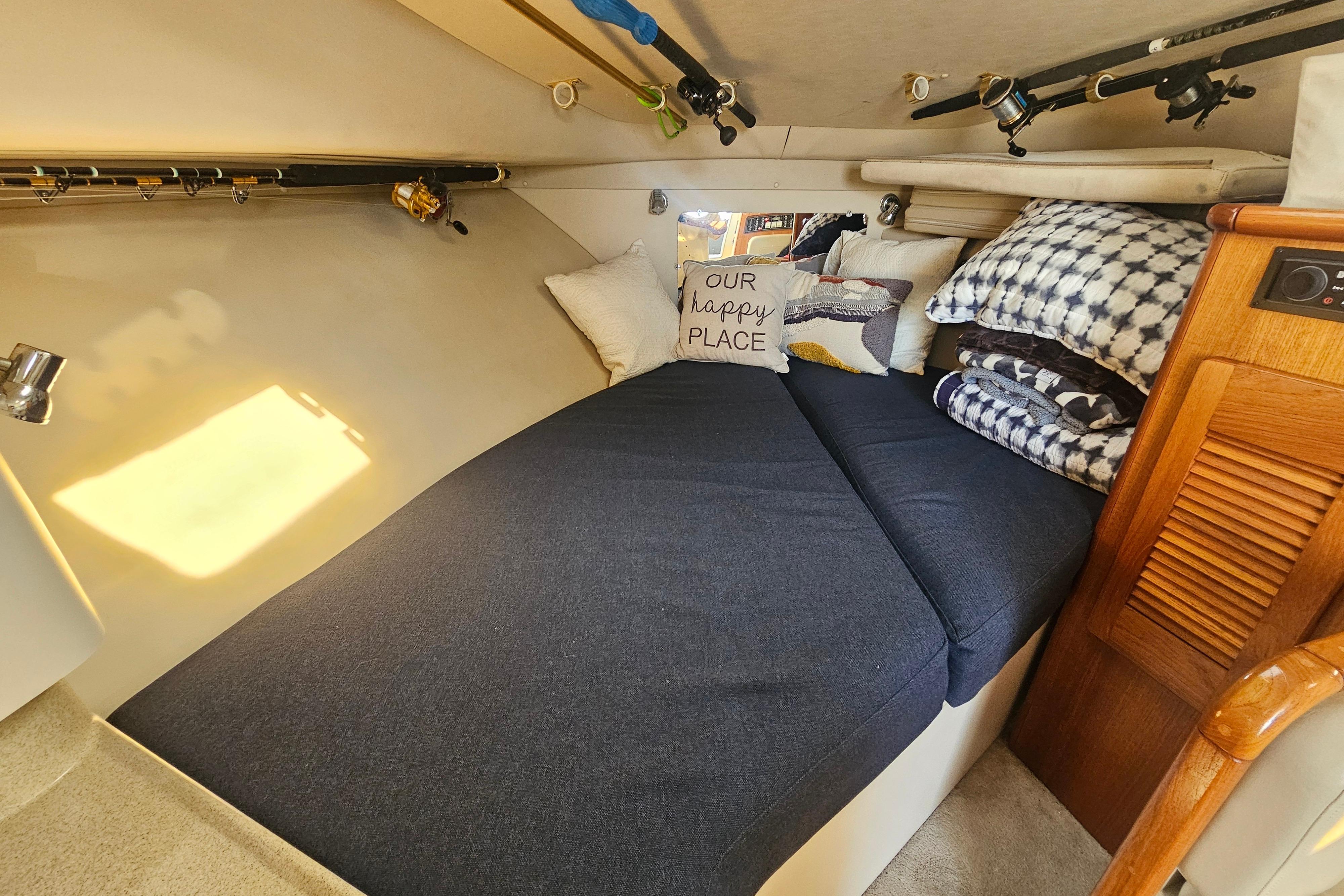 Cozy cabin interior of 2001 Pursuit 3000 Express with bed and fishing rods.