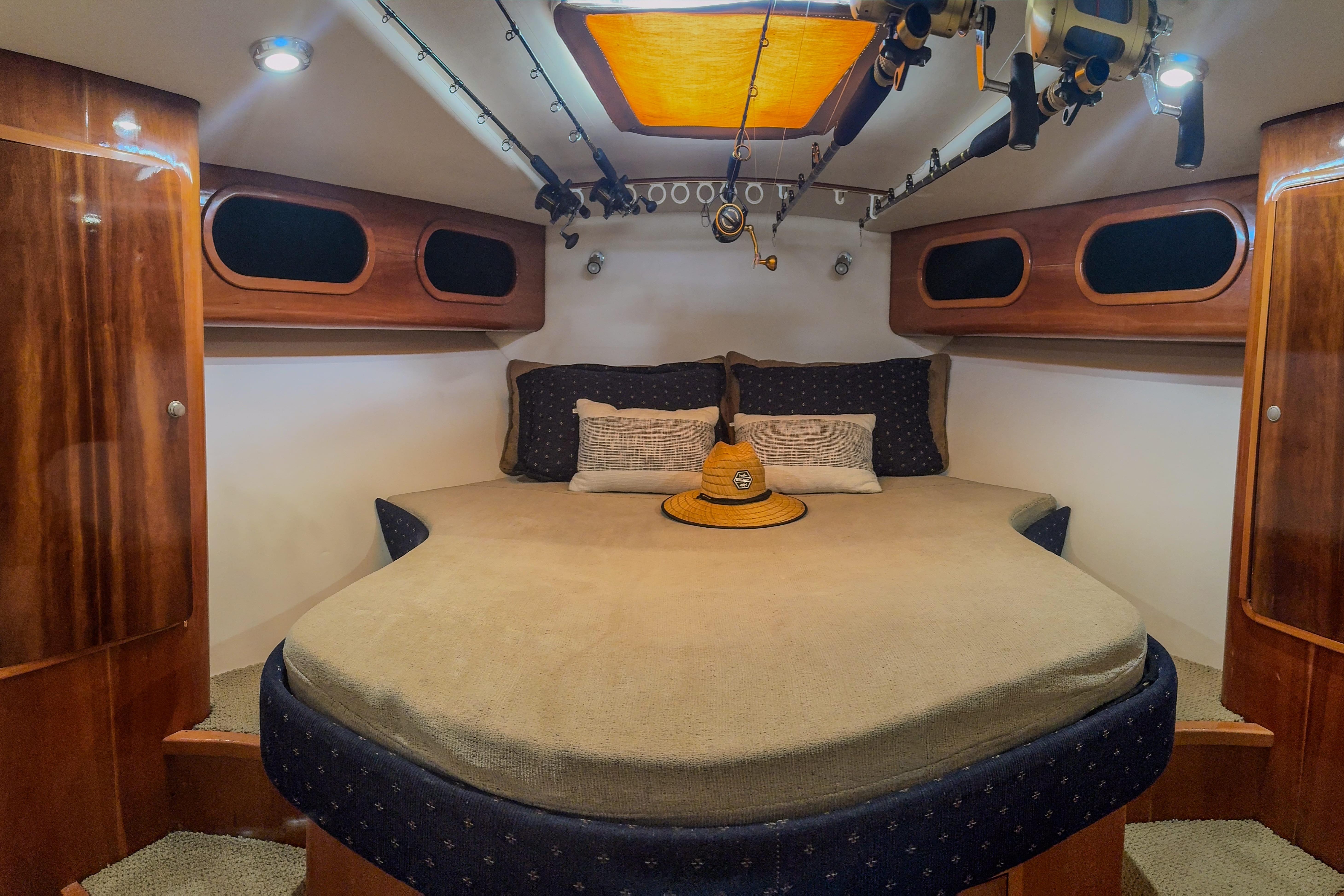 Luxurious cabin interior of 2001 Black Watch 40 boat with cozy bed and fishing rods.