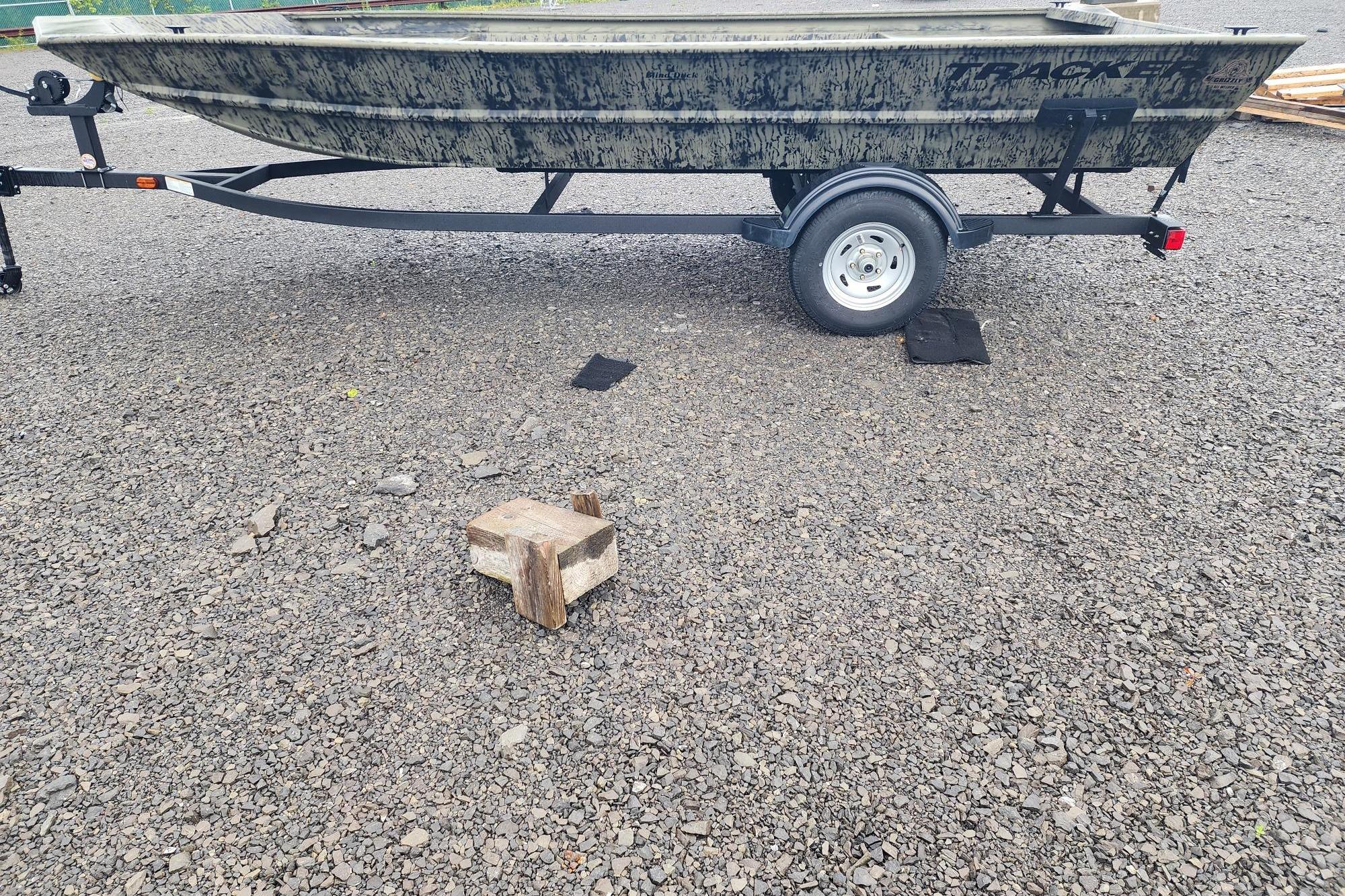2026 Tracker Grizzly 1754 Utility boat on trailer, parked on gravel surface.
