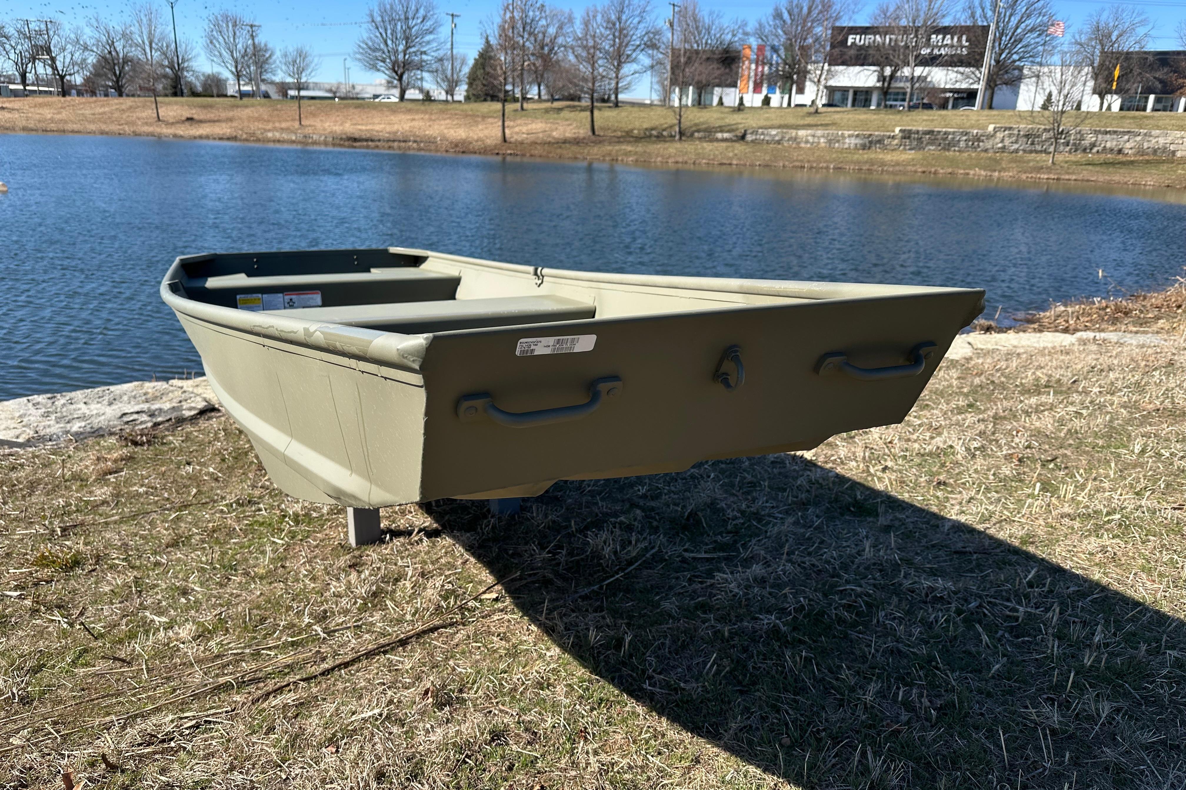 2026 Tracker Grizzly 14 Jon boat by a serene lake, grassy shore, clear sky.
