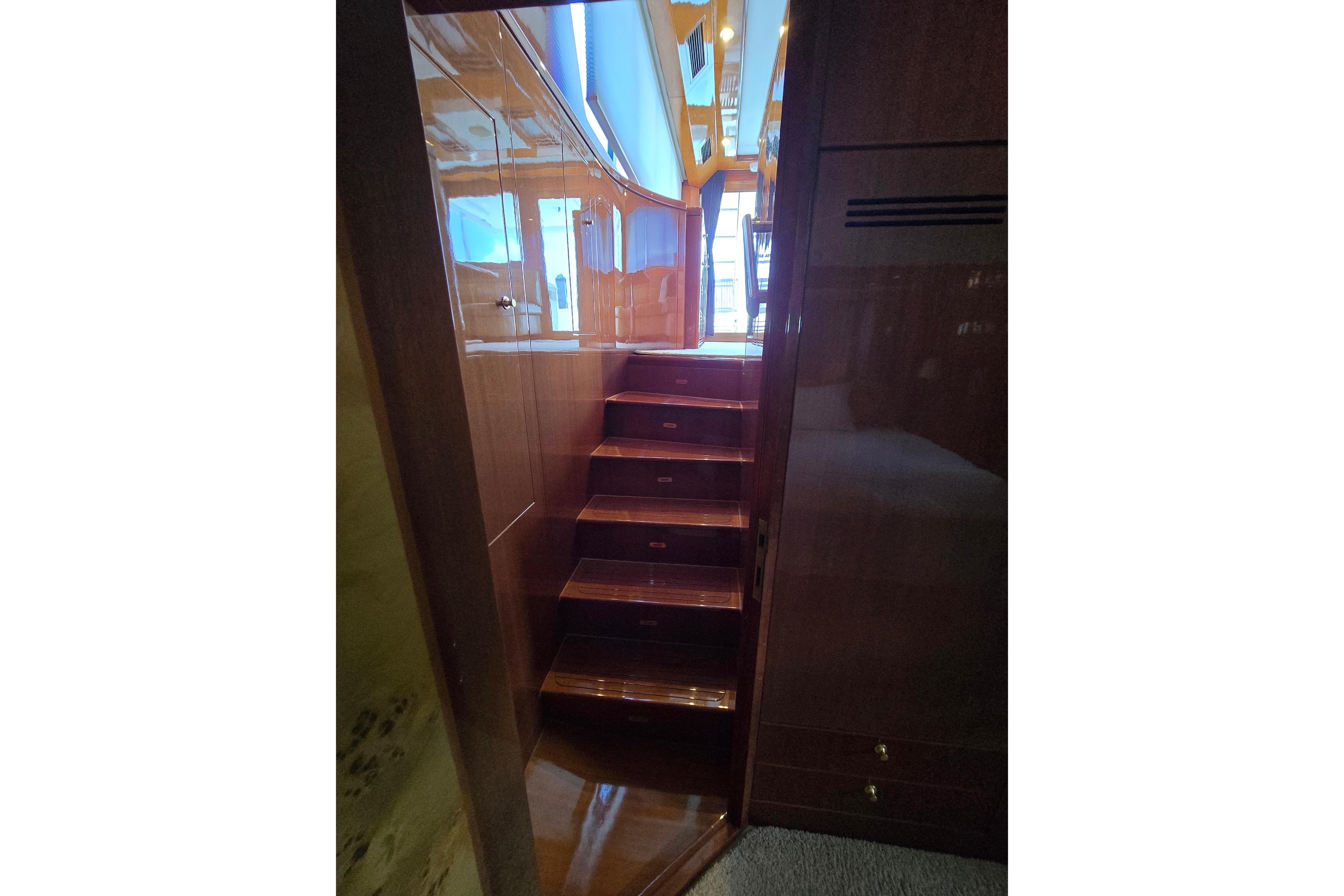 Interior wooden staircase on a 2004 Grand Harbour 58 yacht, leading to upper deck.