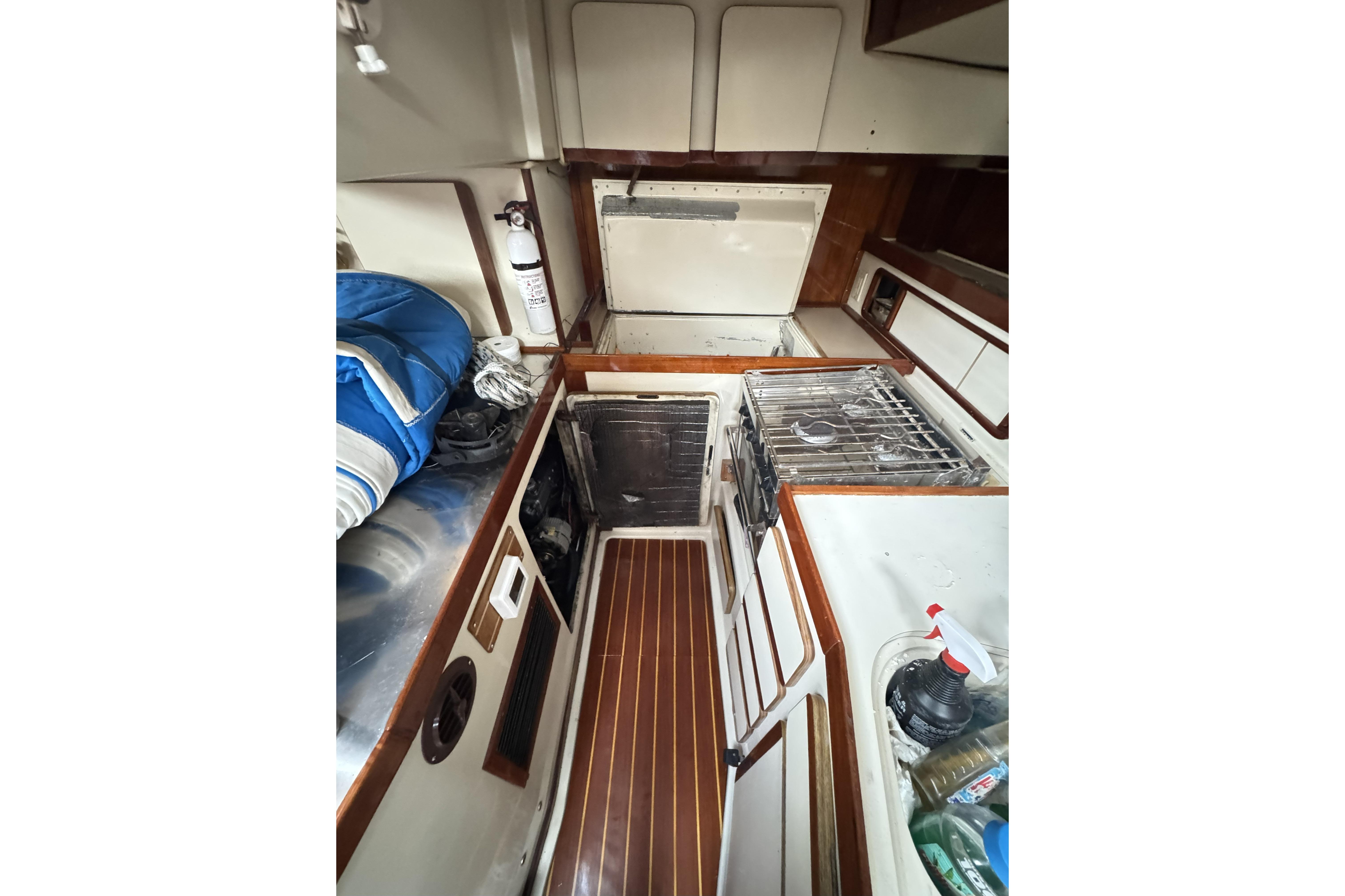 Interior of 1987 Irwin 38 sailboat galley with stove, storage, and wooden flooring.