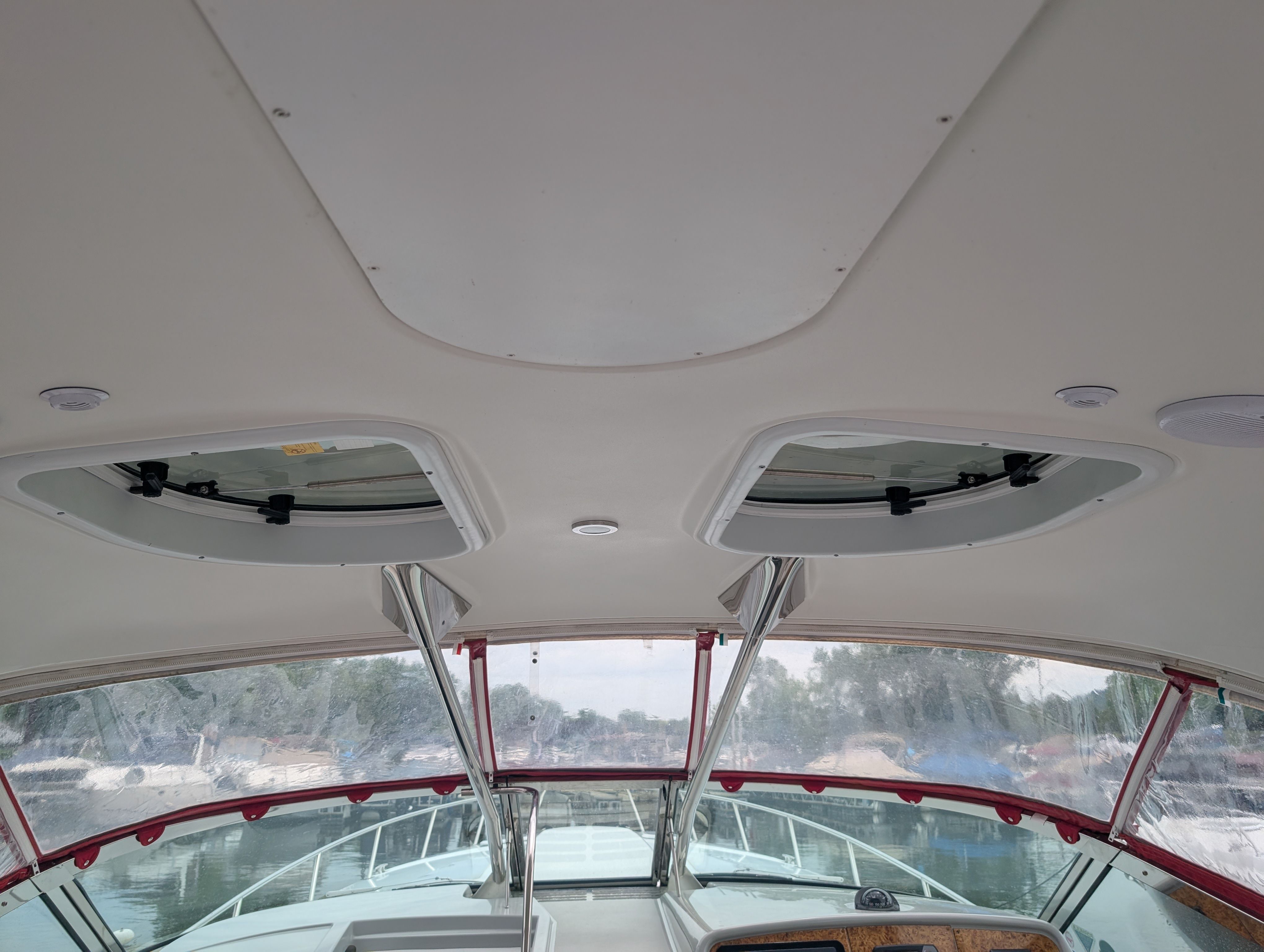 The image shows a boat cockpit with two skylights and a clear view outside.
