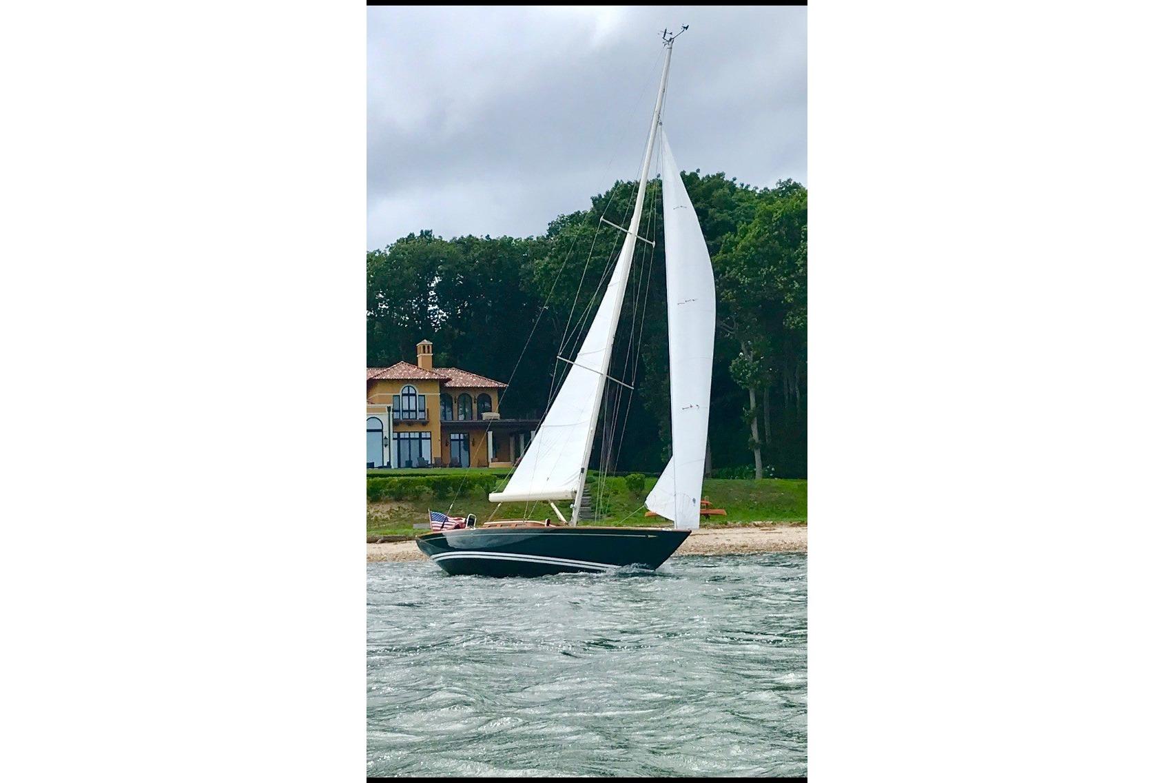 Sailing yacht Morris 36 (2006) on water near a coastal house with lush greenery.