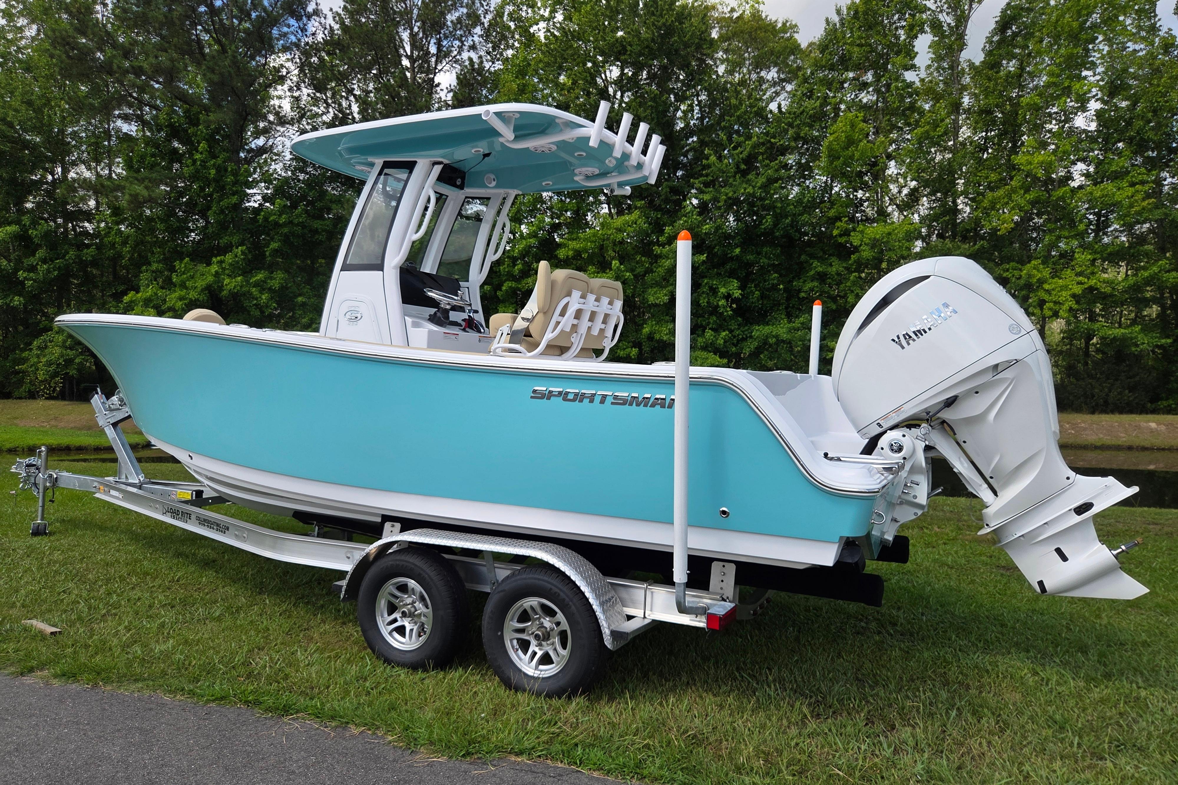 2026 Sportsman Open 232 Center Console boat on trailer, parked on grass.
