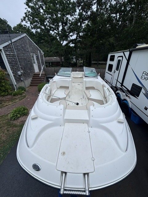 A 2003 Glastron DX 235 boat is on a trailer next to an RV.