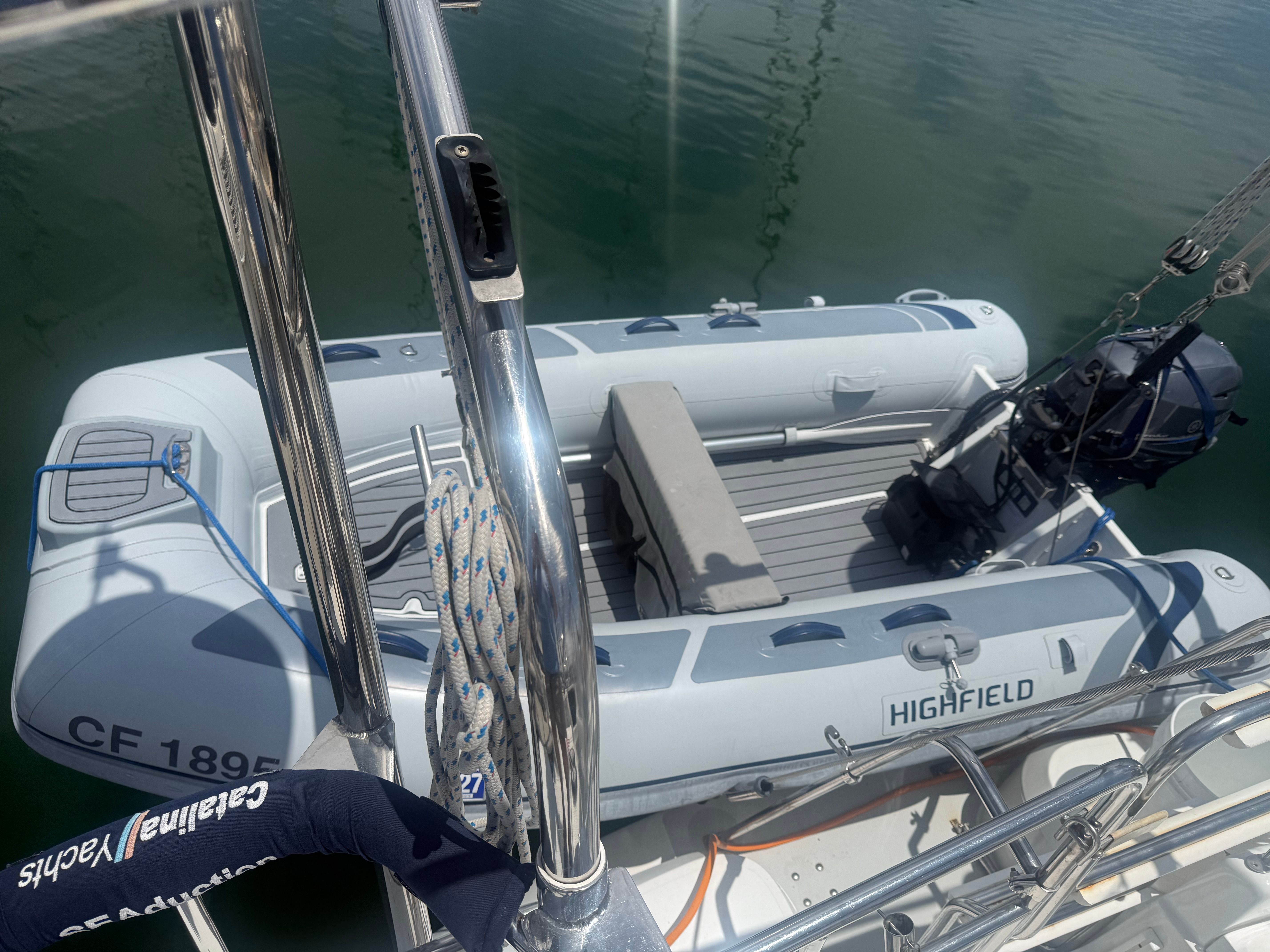 A gray inflatable boat by Highfield, model Classic 310, is in the water next to a larger boat.