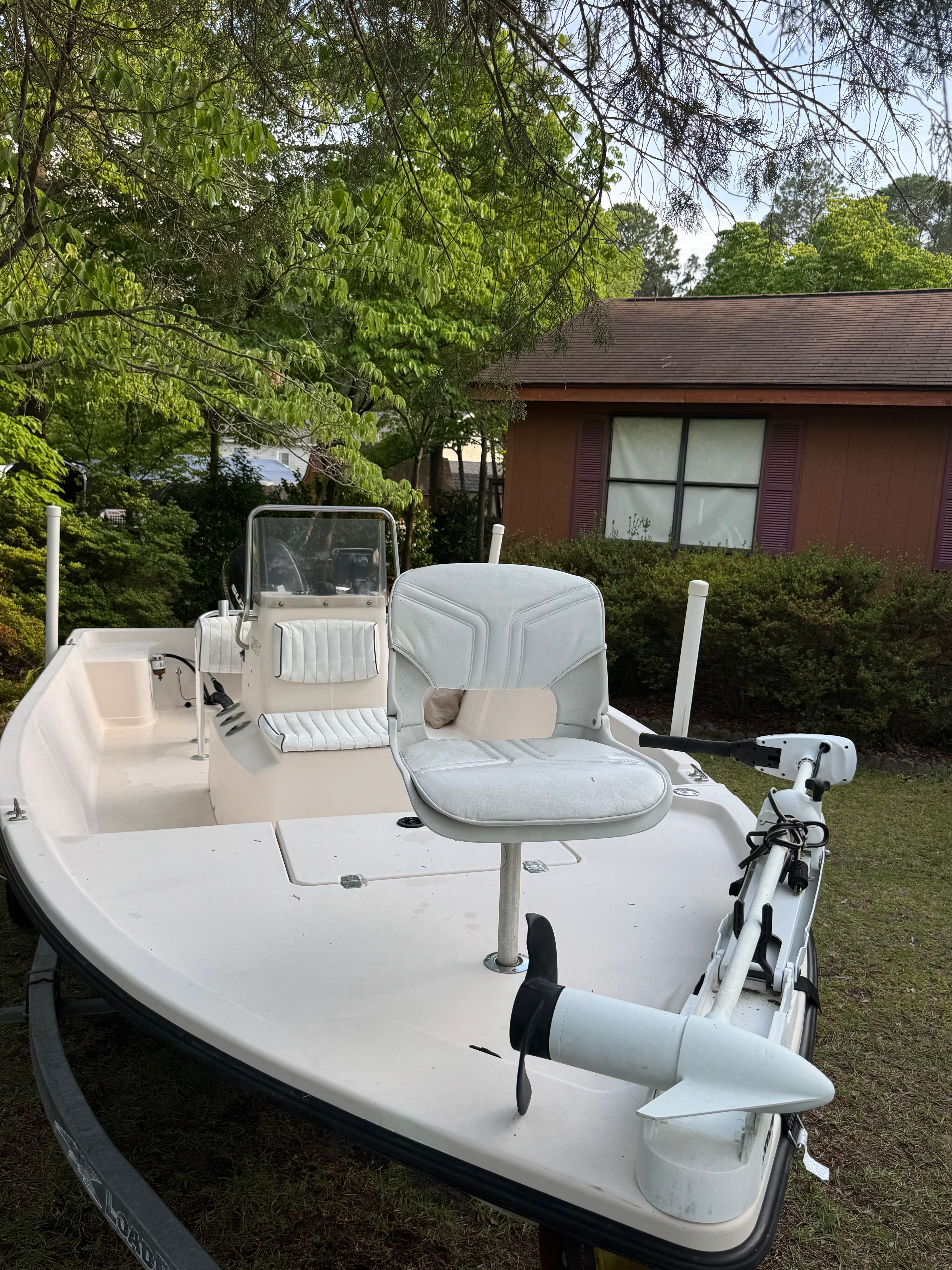 A 2002 Maverick Pathfinder 1806 V boat on a trailer in a green garden setting.