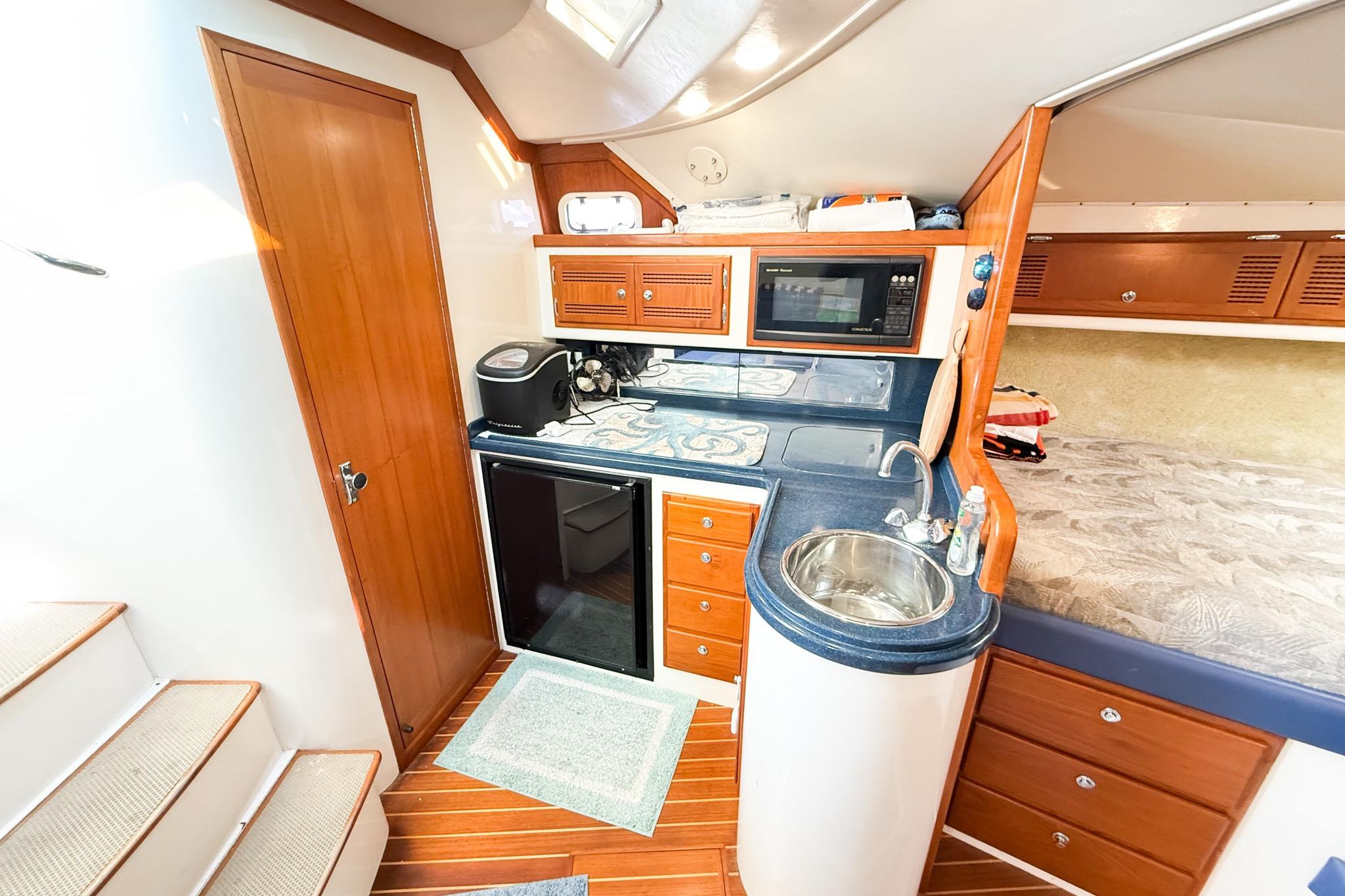Interior of 1996 Cabo 35 Express yacht with kitchenette and wooden cabinetry.