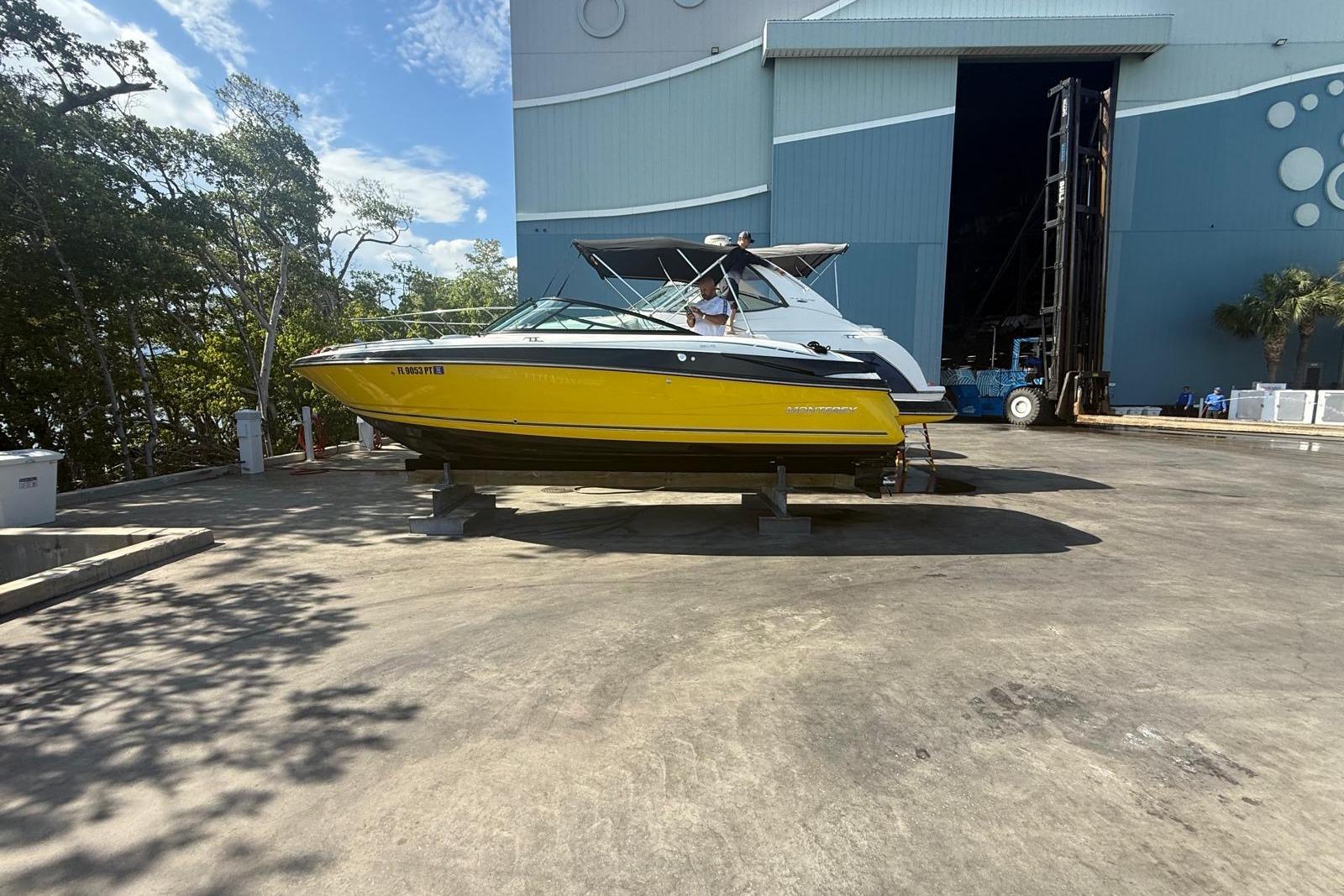 2015 Monterey 264FS boat in yellow, parked outside a large warehouse.