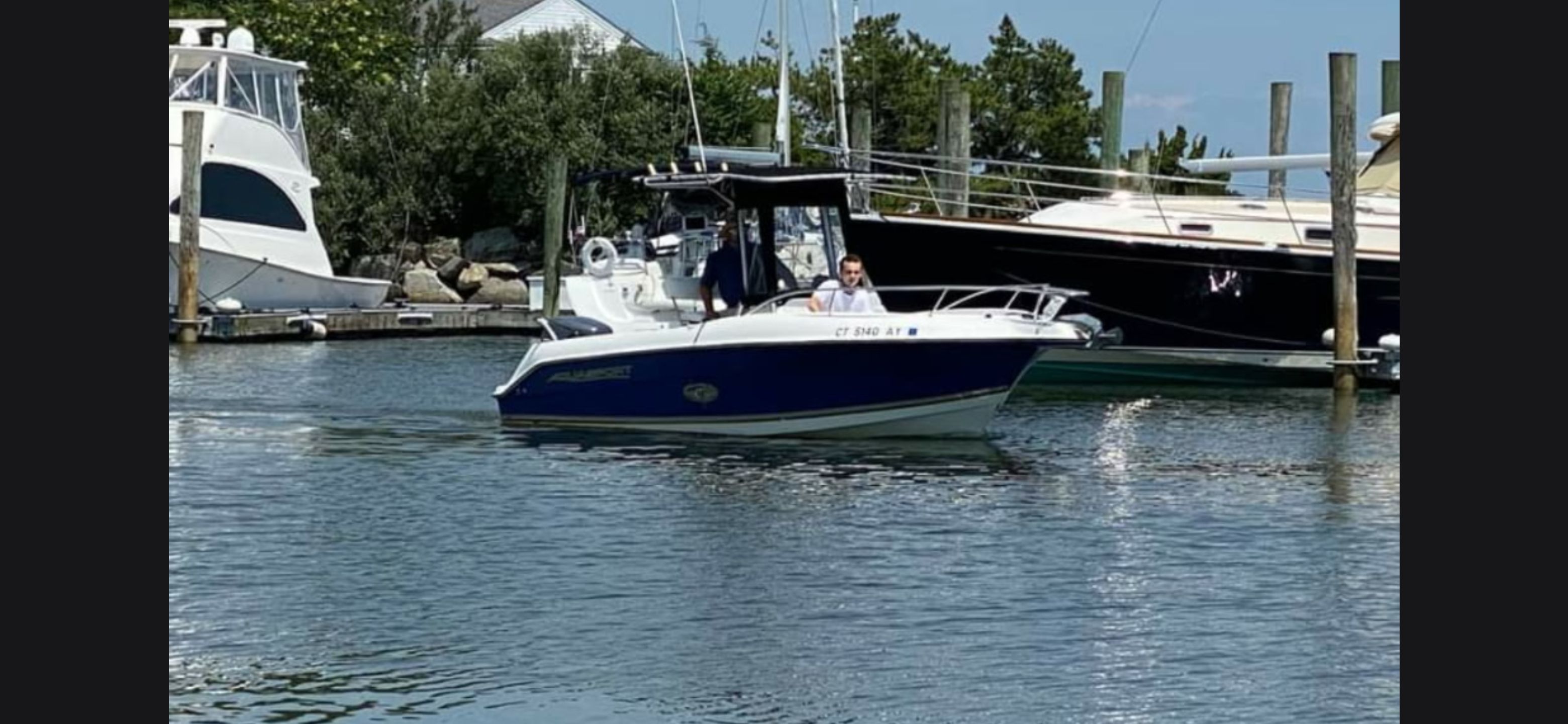 A 2003 Aquasport 205 Osprey on calm water, surrounded by other boats.