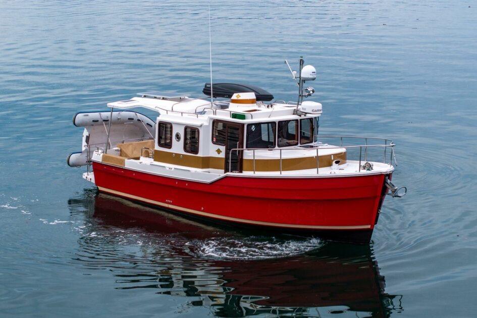 2019 Ranger Tugs R-31-S boat cruising on calm water, featuring a vibrant red hull.