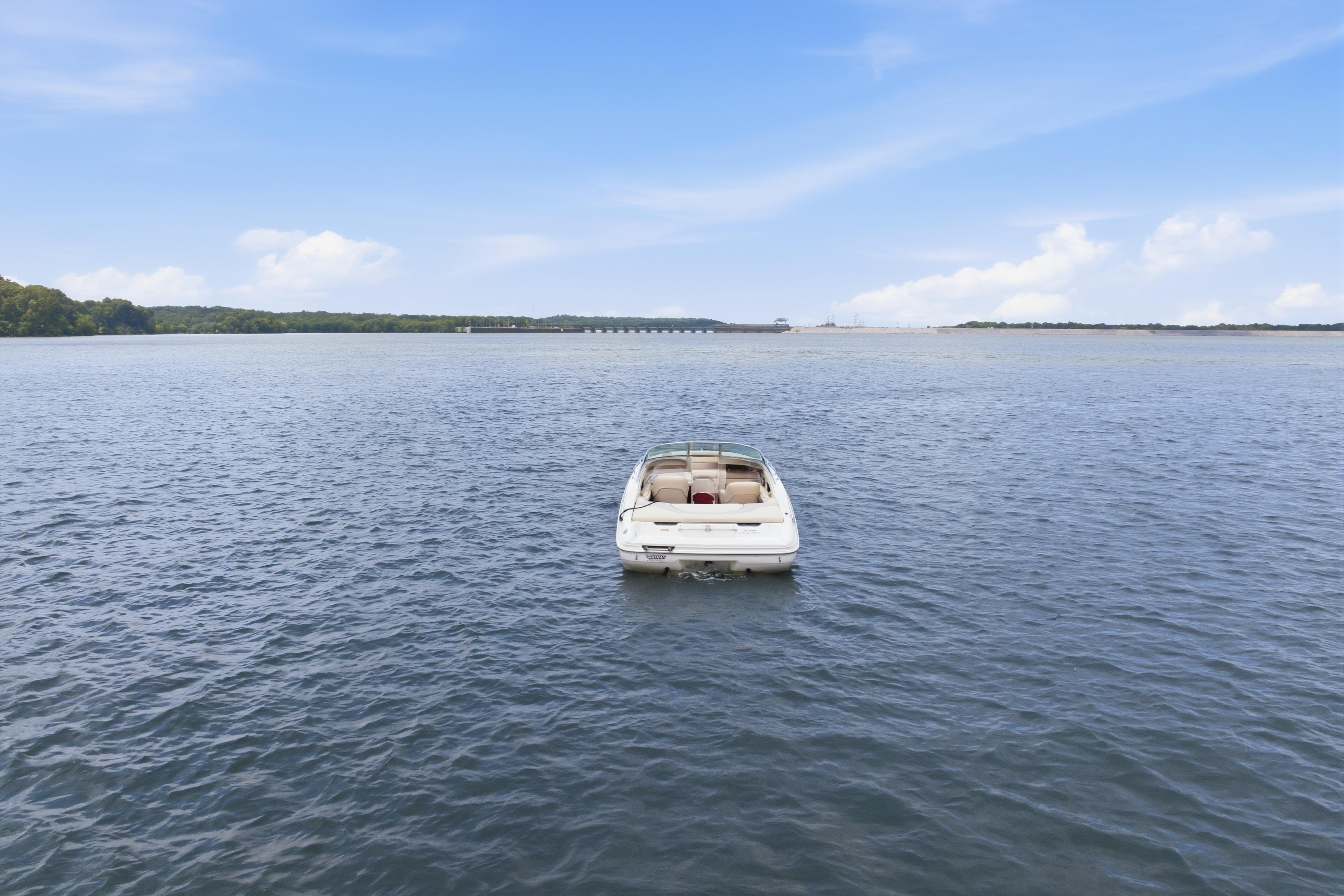 1997 Sea Ray 230 Signature boat on calm water under blue sky.