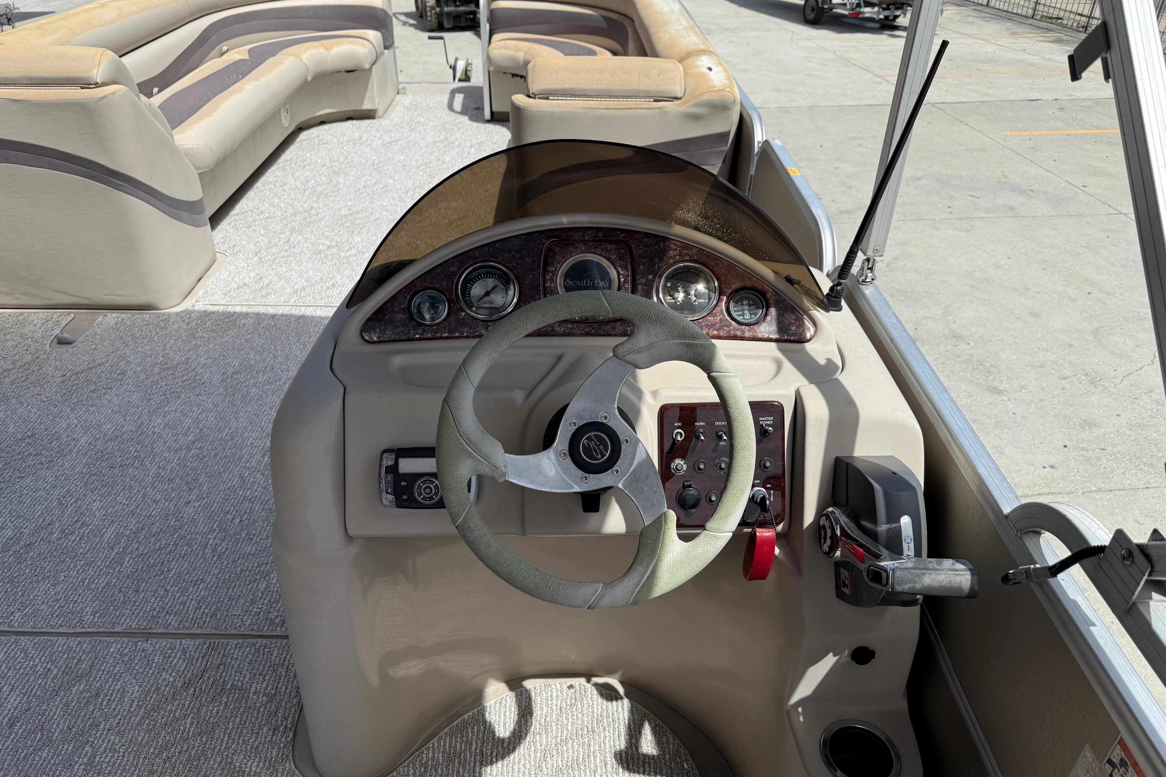 Steering console of a 2012 South Bay 522 CR pontoon boat with beige seating.
